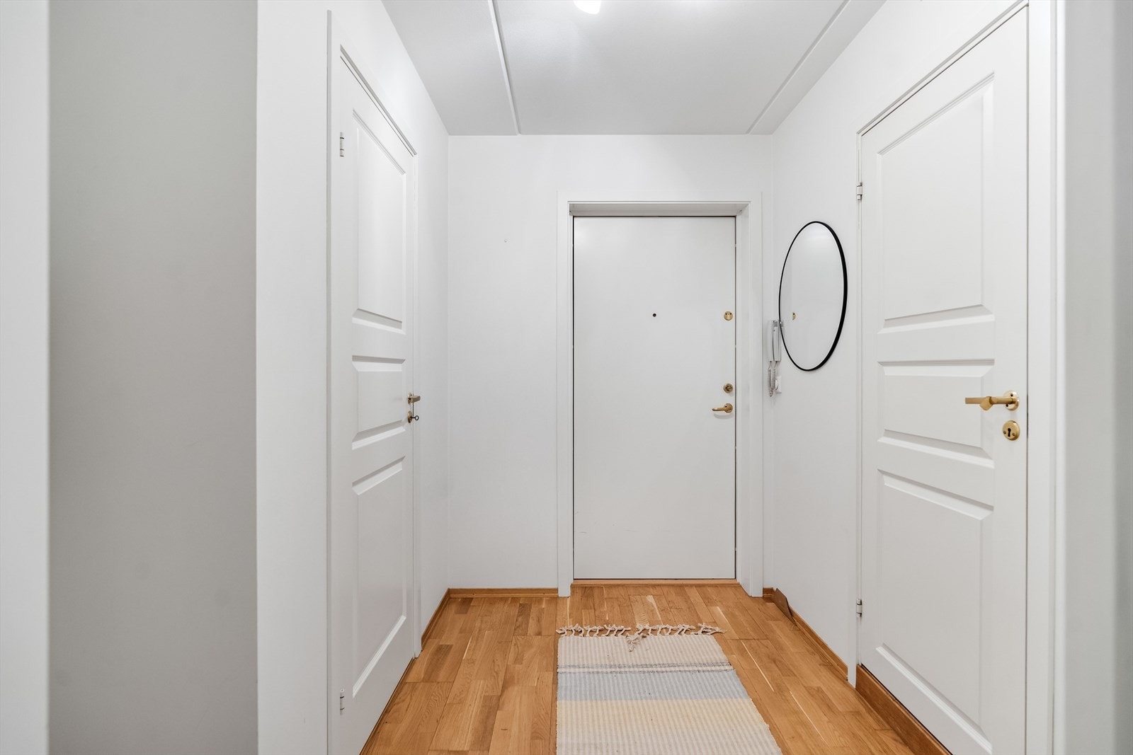 Entreen er innredet med porttelefon, parkettgulv og hvitmalte vegger. Her er det plass til å sette fra seg skoene og henge fra seg yttertøyet. Galleribilde