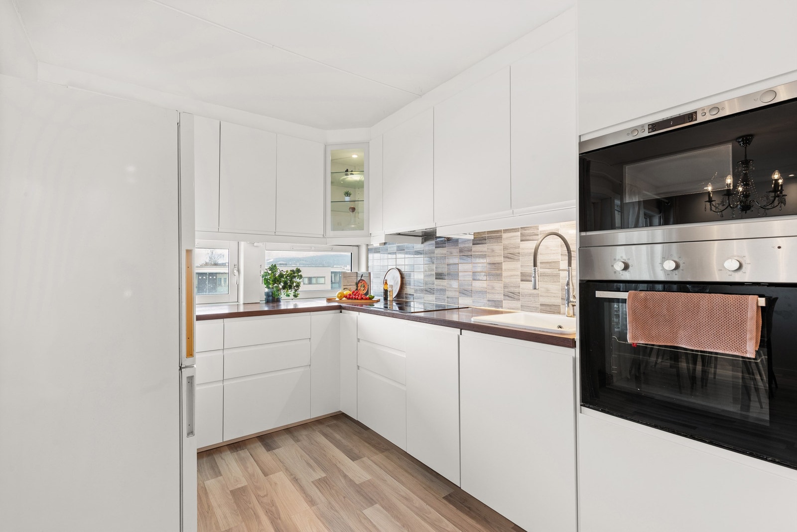 Kjøkkenet har rikelig med skap- og benkeplass. Laminat benkeplate med nedfelt vaskekum. Fliser på vegg over benkeplate. Galleribilde