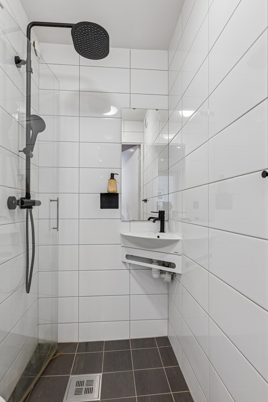 Badet er innredet med toalett, dusjdør og servant med speil. Galleribilde