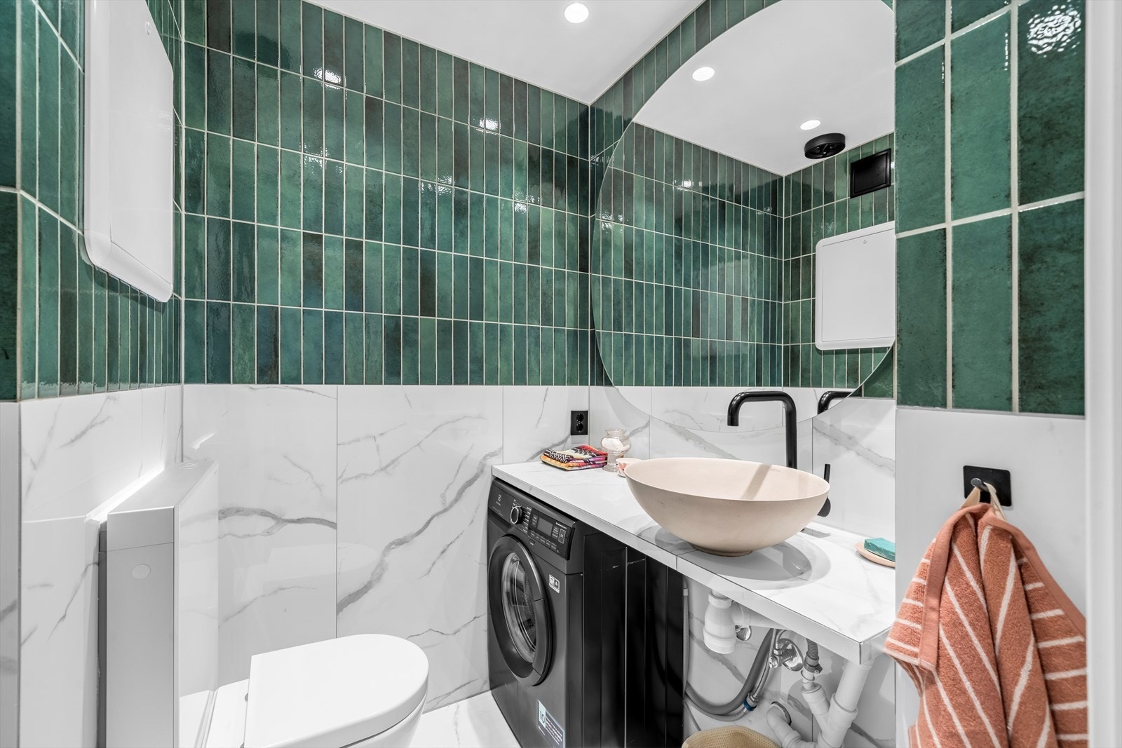 Badet er innredet med servant, speil over servant, vegghengt toalett, dusj på gulv samt opplegg for vaskemaskin. Galleribilde