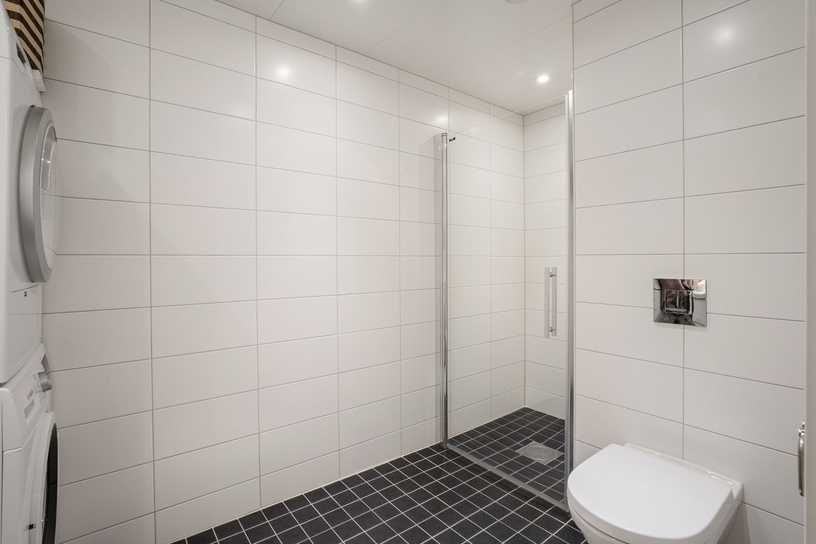 Baderommet er utstyrt med gulvvarme, en baderomsinnredning med servant og blandebatteri, speil og belysning. Videre finnes et dusjnisje med glassdør og et vegghengt toalett. Galleribilde