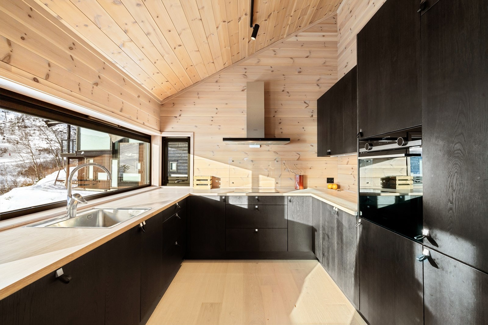 Et meget innholdsrikt kjøkken med mye skap og lagringsplass, samt arbeidsbenk. Her nyter kokken den fantastiske utsikten og de gode lysforholdene - mens en kan følge barnas lek utenfor. Galleribilde