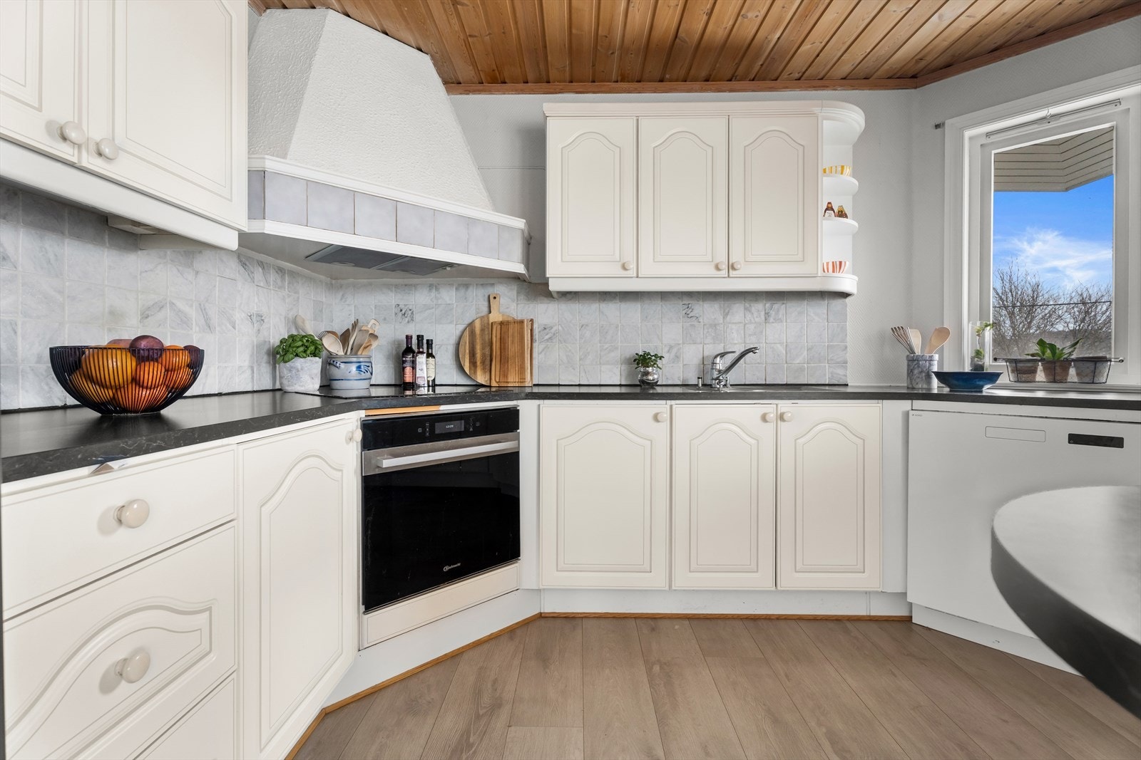 Kjøkkeninnredningen har hvite, profilerte fronter og en laminert benkeplate med underlimt vask. Galleribilde