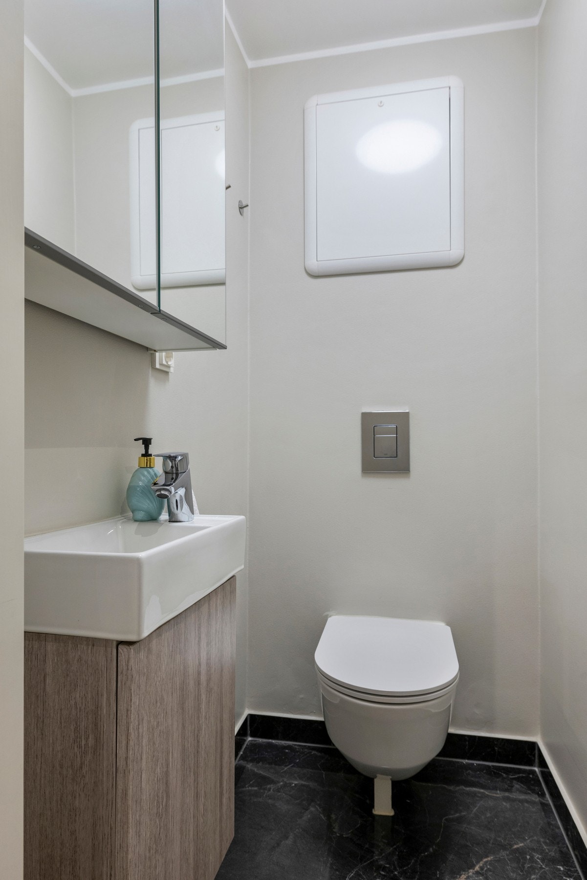 Toalettet har et vegghengt klosett med innebygd sisterne og servant med speilskap over Galleribilde