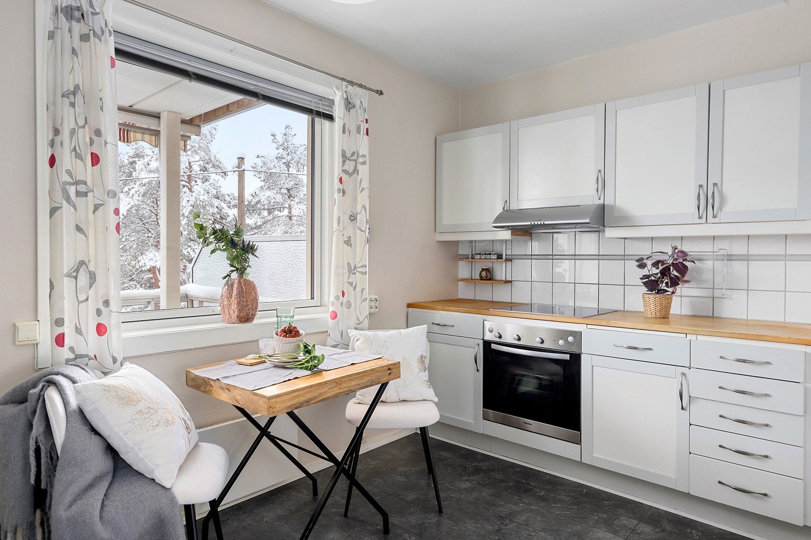 Romslig kjøkken med lyse overflater og benkeplate i tre. Galleribilde