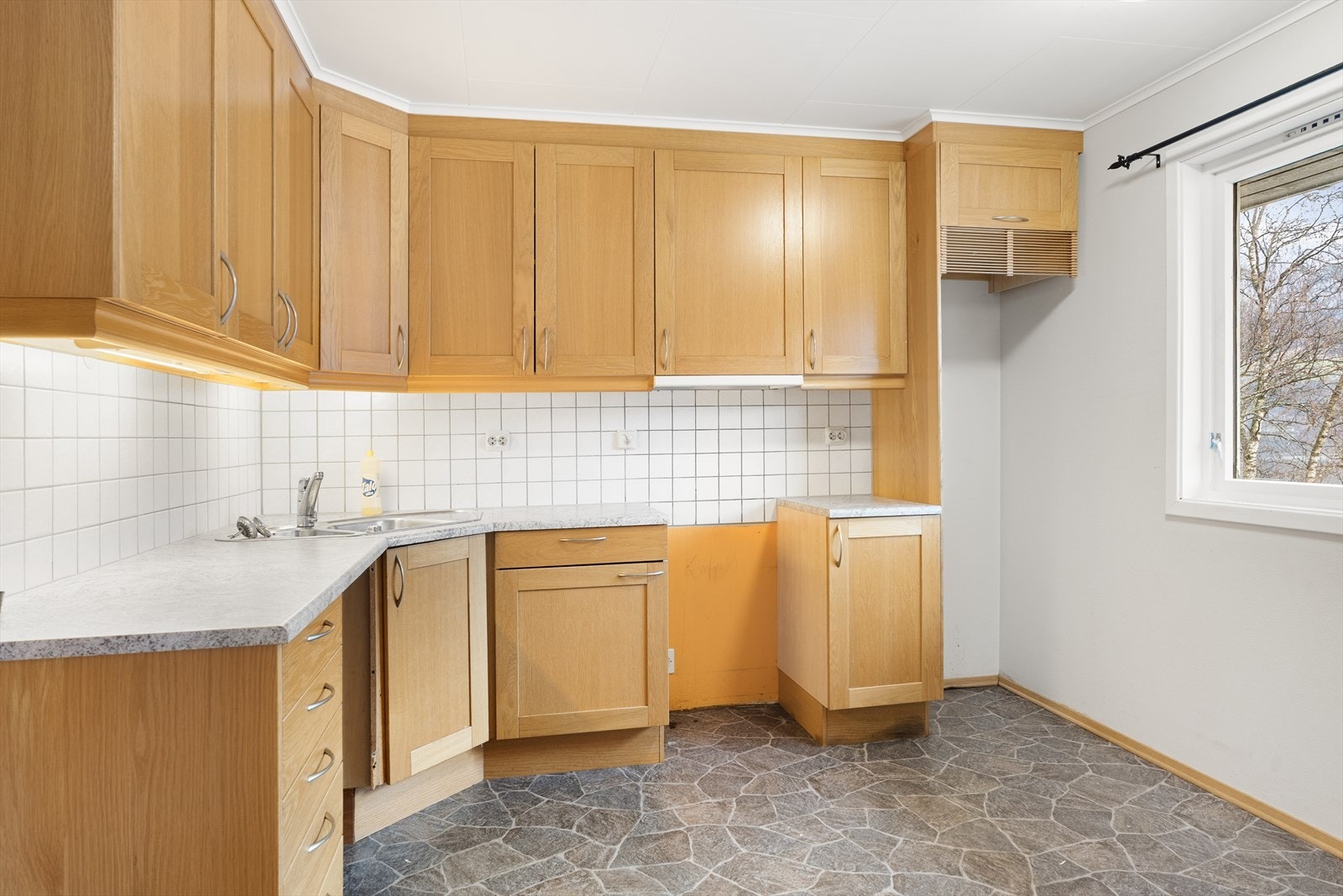 Pent kjøkken med innredning i med eikestruktur og lys benkeplate Galleribilde