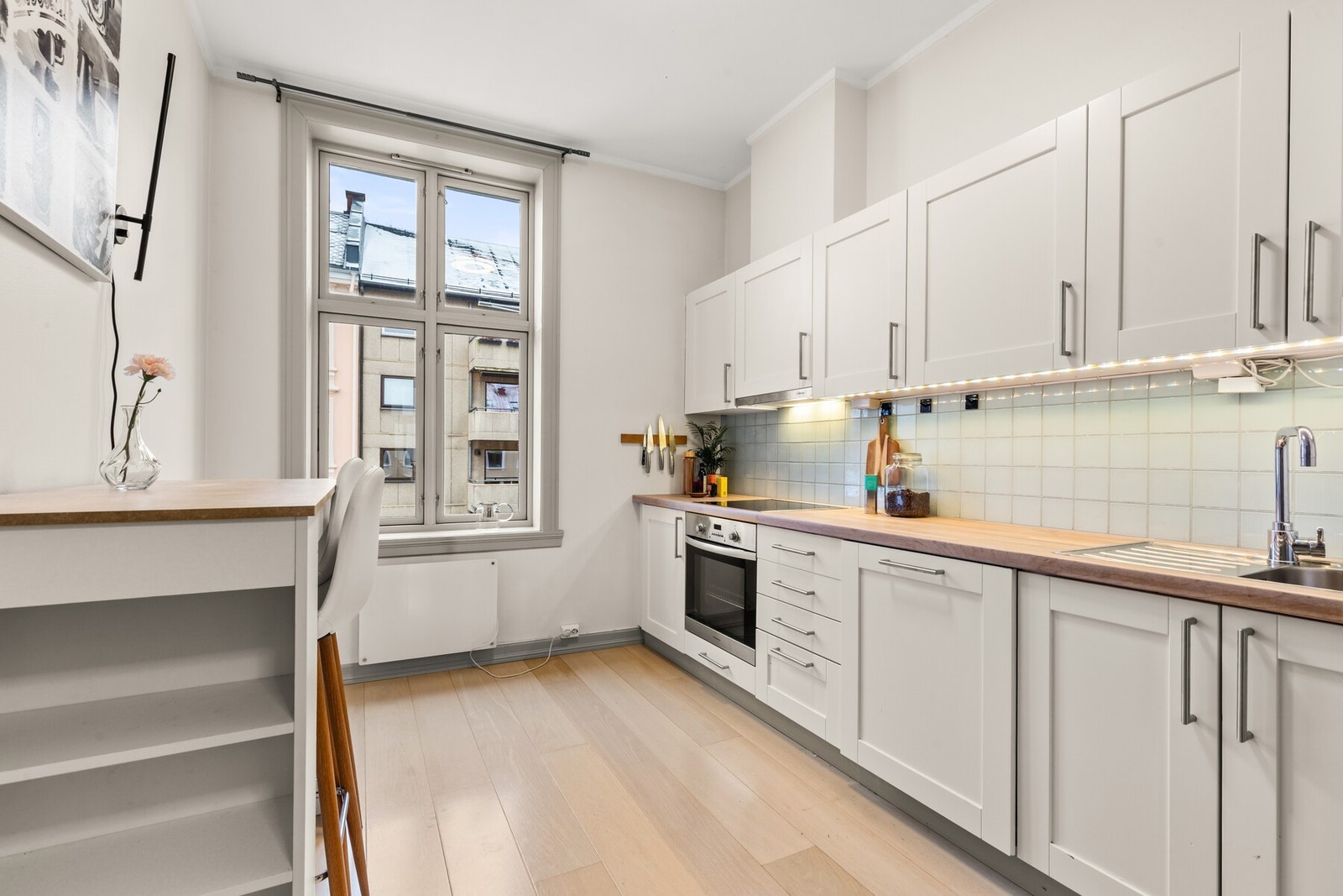 Integrerte hvitevarer bestående av stekeovn, nedfelt induksjonstopp, oppvaskmaskin og plass til frittstående kjøl/frys. Galleribilde