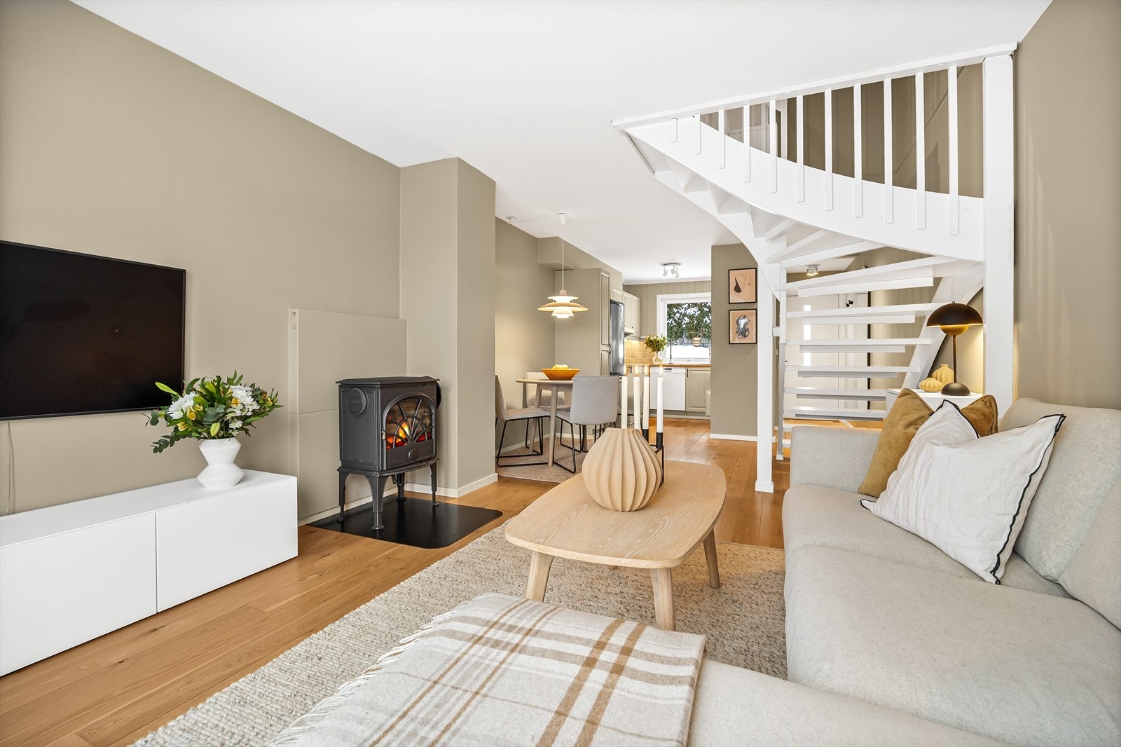 Stue og kjøkken ligger i åpen løsning, med naturlige møbleringssoner for både sofa og spisebord Galleribilde