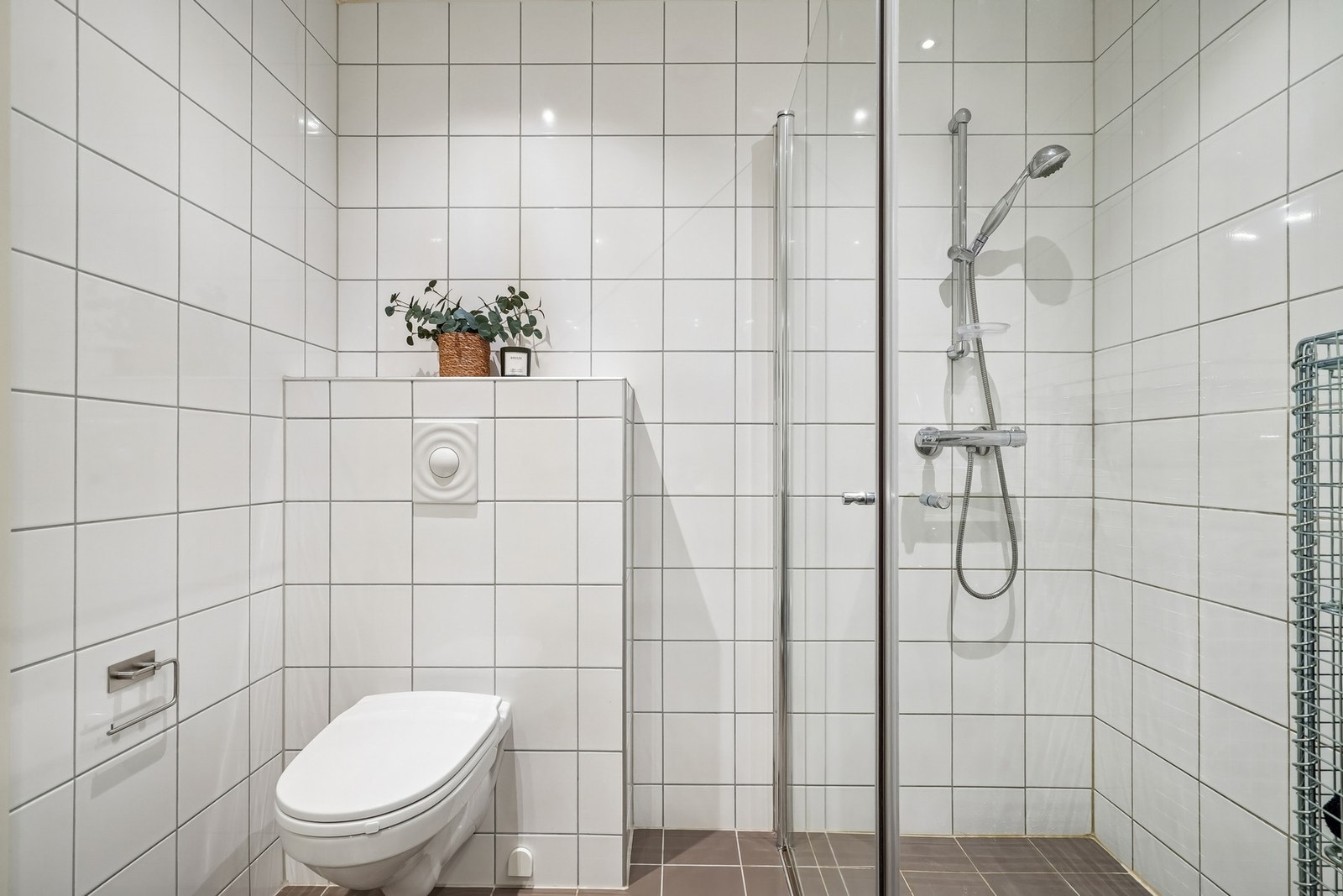 Badet er utstyrt med vegghengt toalett og dusjhjørne med innsvingbare dusjdører. Galleribilde