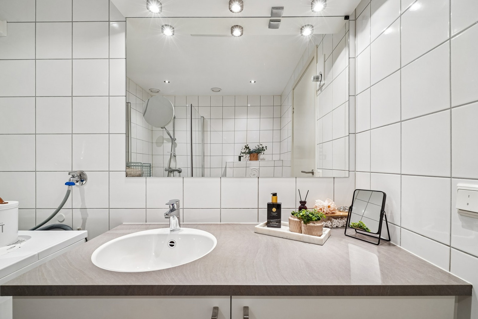 Romslig baderomsmøbel med hvite fronter, underlimt oppvaskkum og overliggende speil med belysning. Galleribilde