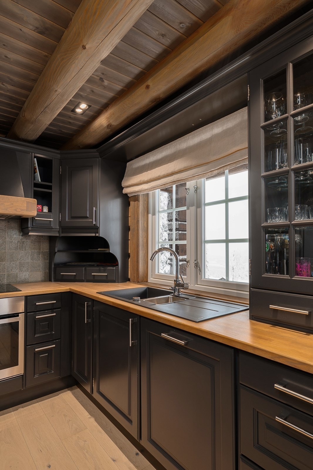 Integrerte hvitevarer og en solid benkeplate i heltre. Fint lys inn over kjøkkenbenken. Galleribilde