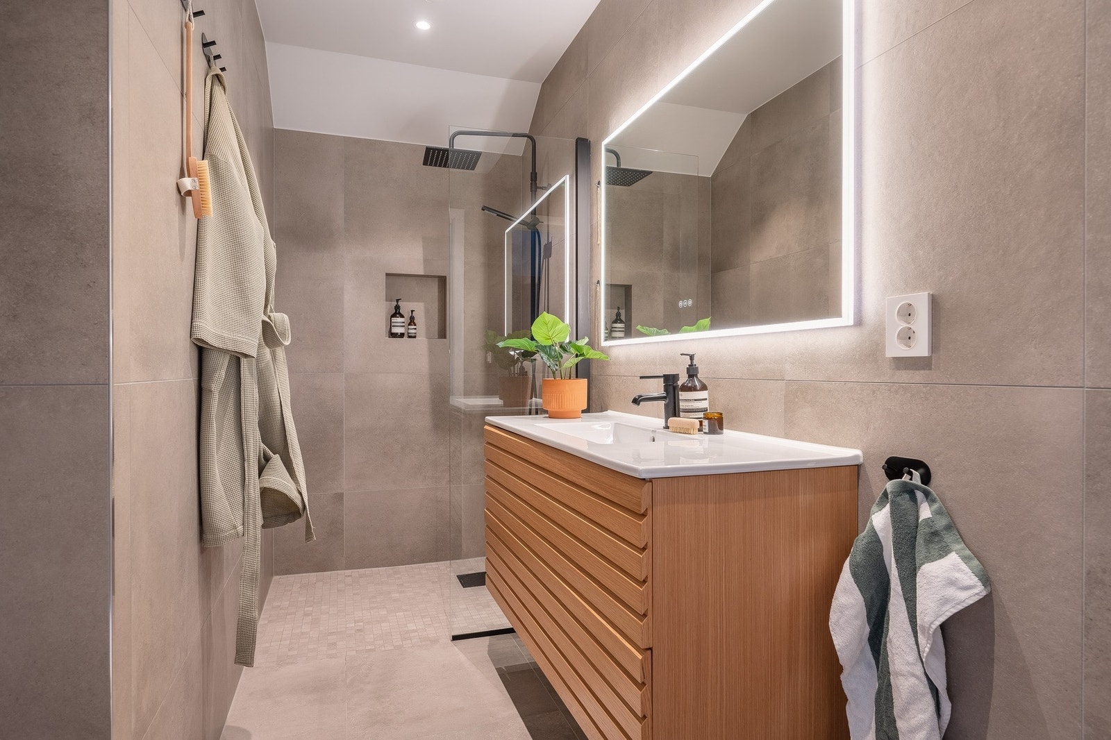 I tilknytning til hovedsoverommet har du et lekkert bad. Store, grå fliser gir rommet et sofistikert uttrykk, mens innredningen er nøye utformet for å kombinere funksjonalitet med stilfullt design. Galleribilde