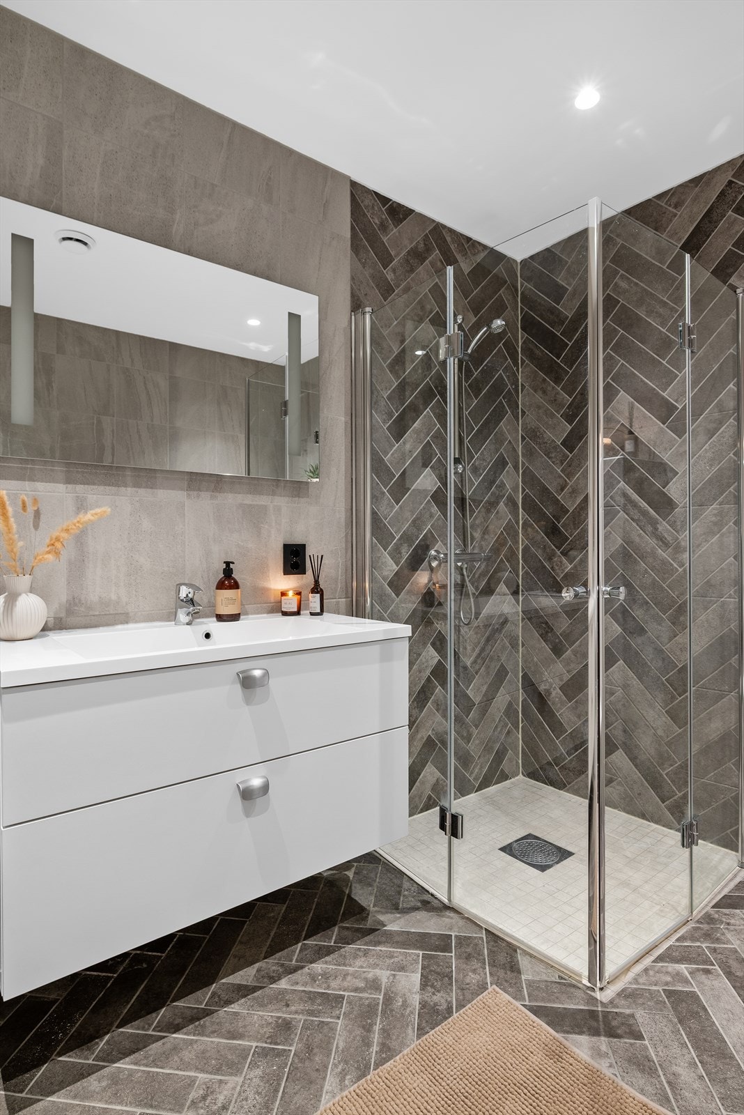 Videre finner du en moderne innredning med heldekkende servant med skuffer under, samt et vegghengt speil med integrert belysning. Galleribilde