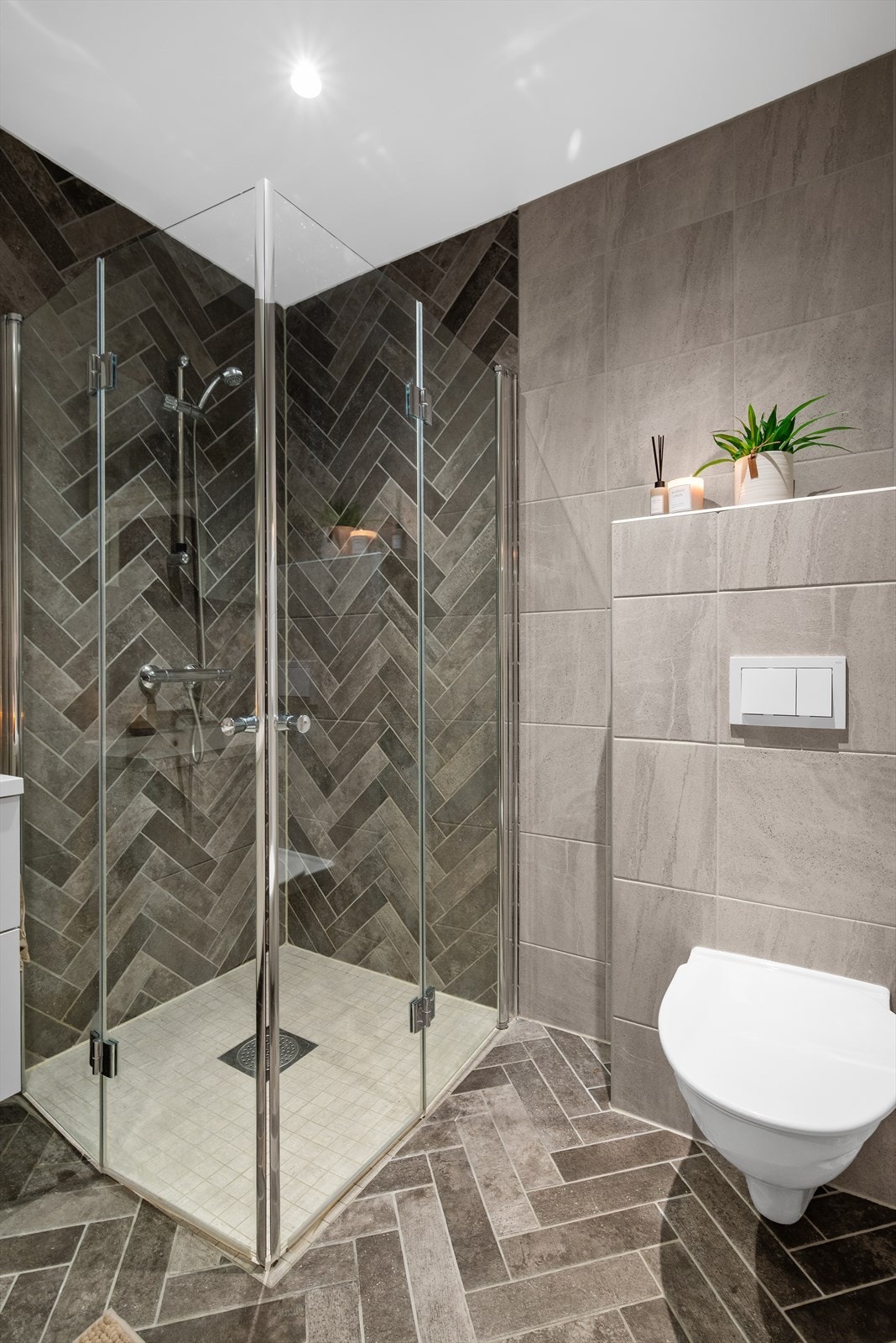 Badet har varmekabler i gulv, praktiske innfellbare dusjdører, vegghengt toalett og opplegg for vaskemaskin. Galleribilde