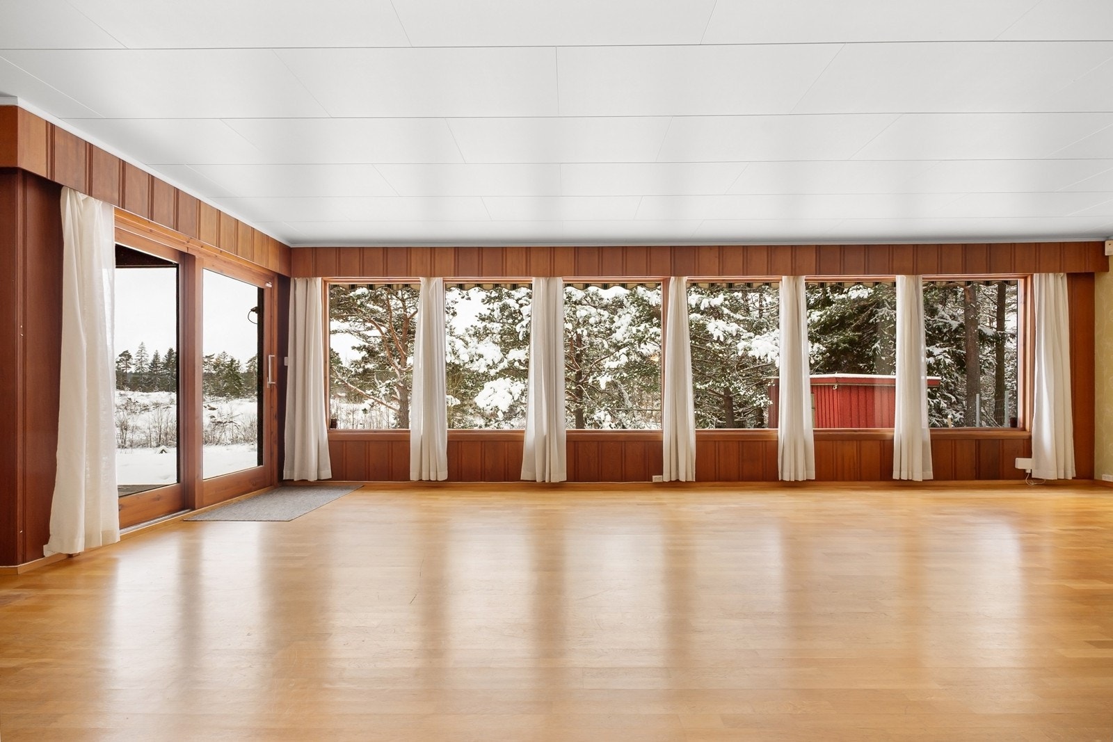 Gjennom en stor verandadør er det utgang til en overbygget, flislagt veranda, med ett trappetrinn ned til en romslig steinlagt uteplass. Uteplassen er vestvendt, med god plass til ønsket utemøblement. Galleribilde