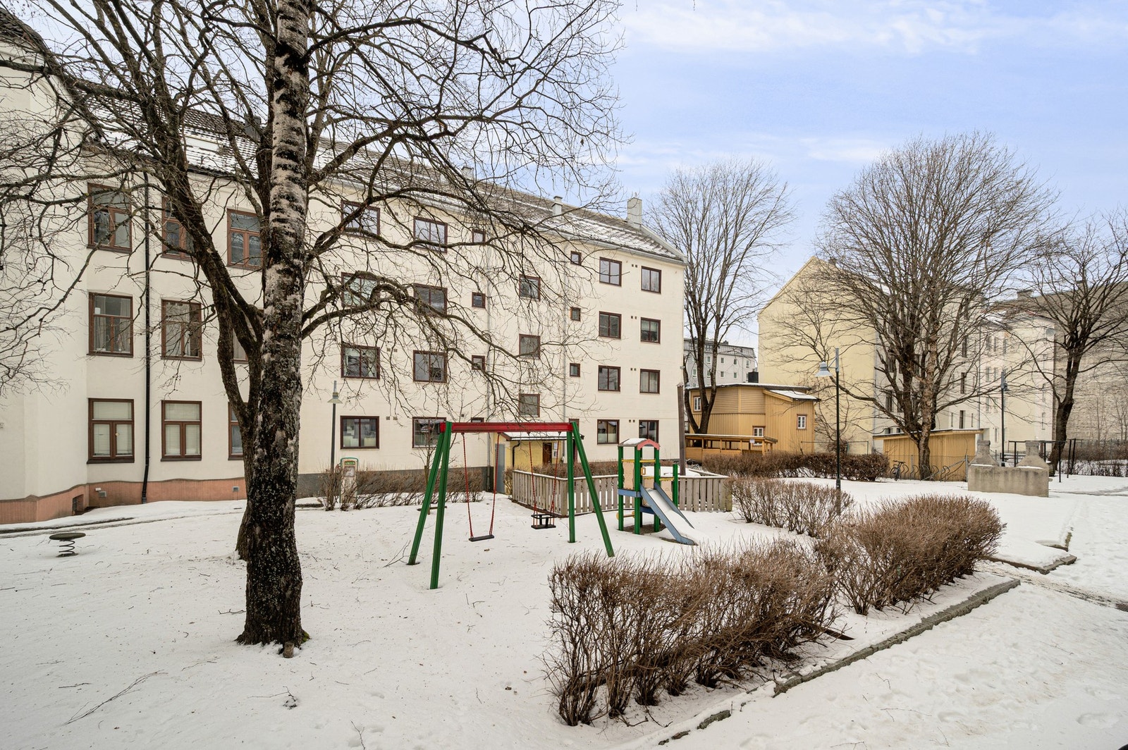 Barnevennlig bakgård med huskestativ, sitteplasser og hyggelig miljø. Galleribilde