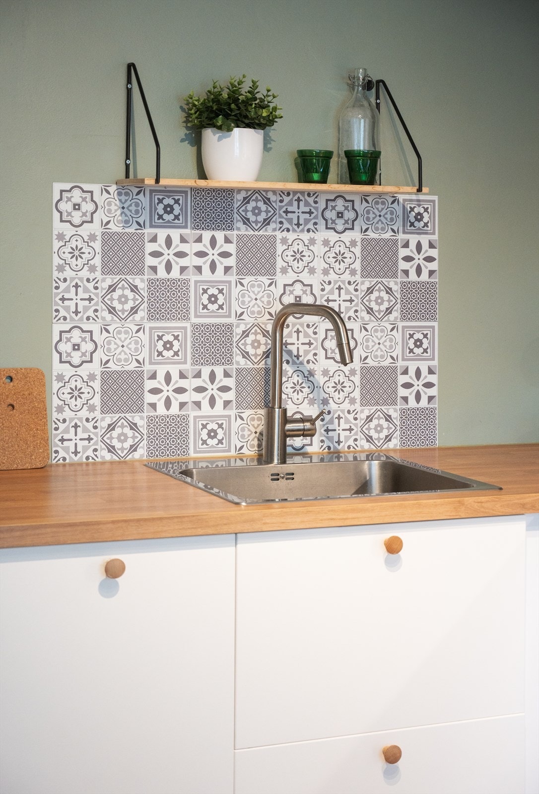 Nedfelt kum i stål med ettgreps blandebatteri og dekorativt belegg over benkeplaten. Galleribilde