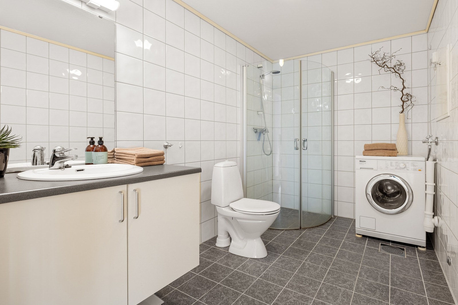 Badet måles til 6,1 kvm. og er helfliset med underliggende varmekabler. Her er det opplegg for vaskemaskin og plass til tørketrommel i tårn. Galleribilde