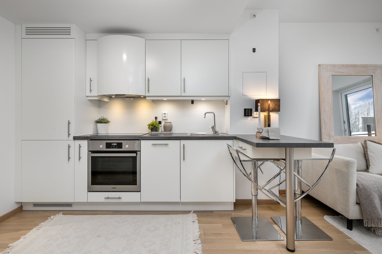 Stilrent kjøkken i åpen løsning mot stuen. Kjøkkeninnredning med hvite glatte fronter. Galleribilde