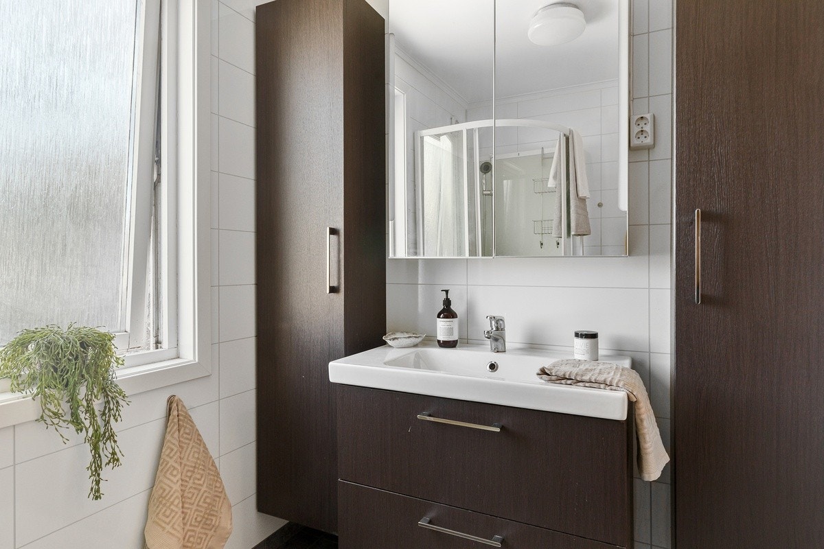 Baderommet har flis på gulv med varme og våtromsplater på vegg. Moderne baderomsmøbler. Galleribilde