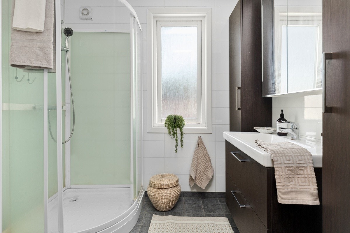 Baderommet har flis på gulv med varme og våtromsplater på vegg. Moderne baderomsmøbler. Galleribilde