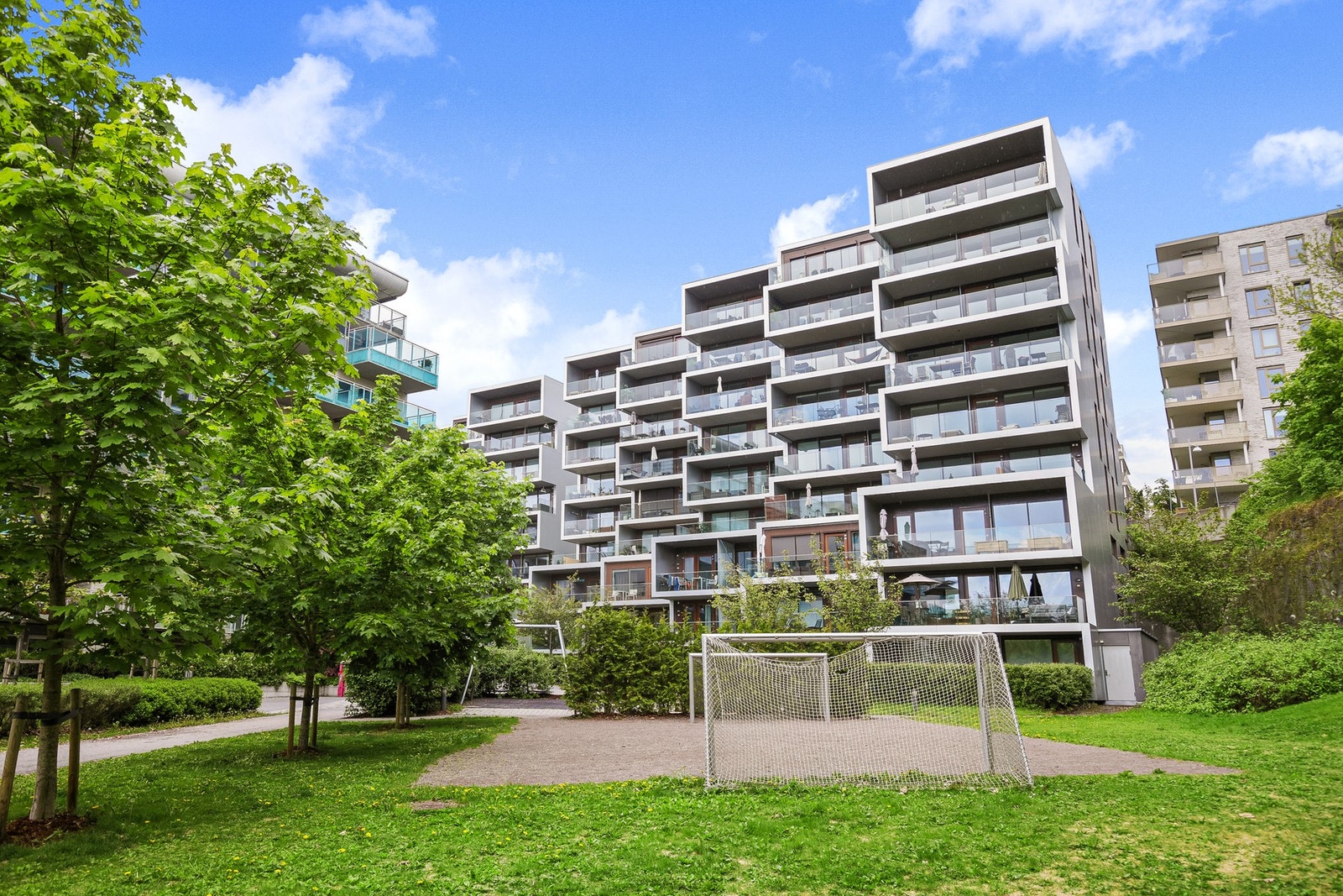 Boligen ligger i et moderne bygg fra 2014 med fokus på bokvalitet og gode innredningsløsninger (sommerbilde). Galleribilde