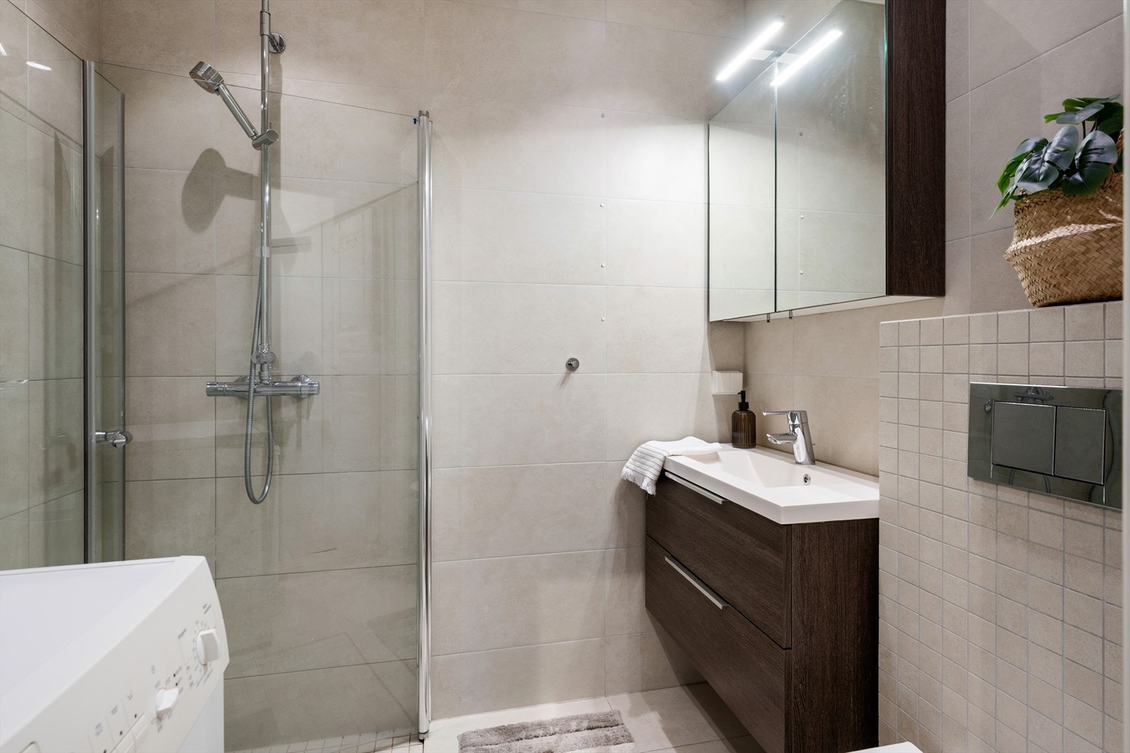 Pent flislagt bad fra 2016 som er innredet med sandfargede fliser på gulv og vegg med underliggende varme i gulv. Galleribilde