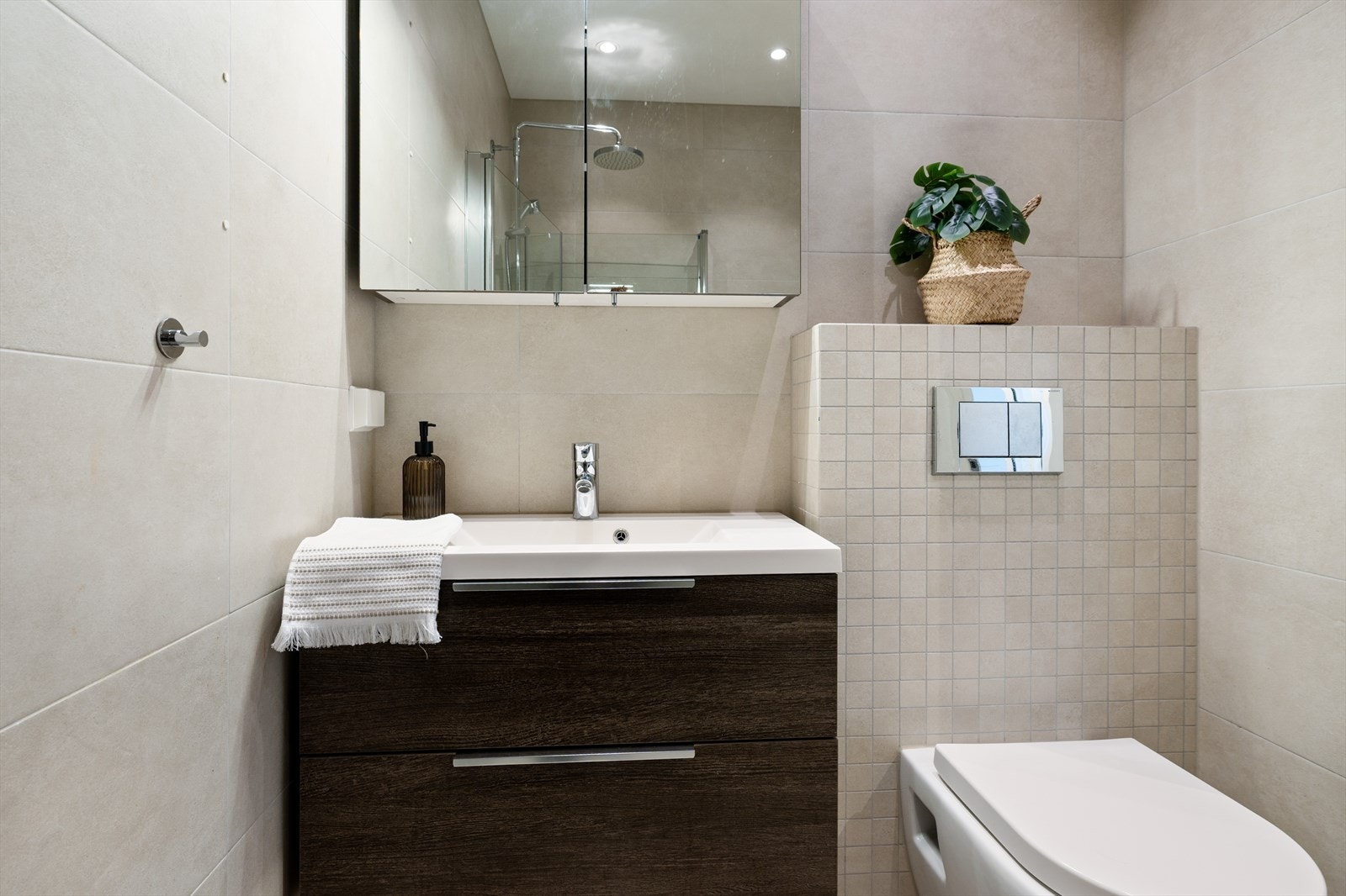 Badet er videre innredet med heldekkende servant, speilskap, vegghengt toalett og downlightsbelysning Galleribilde