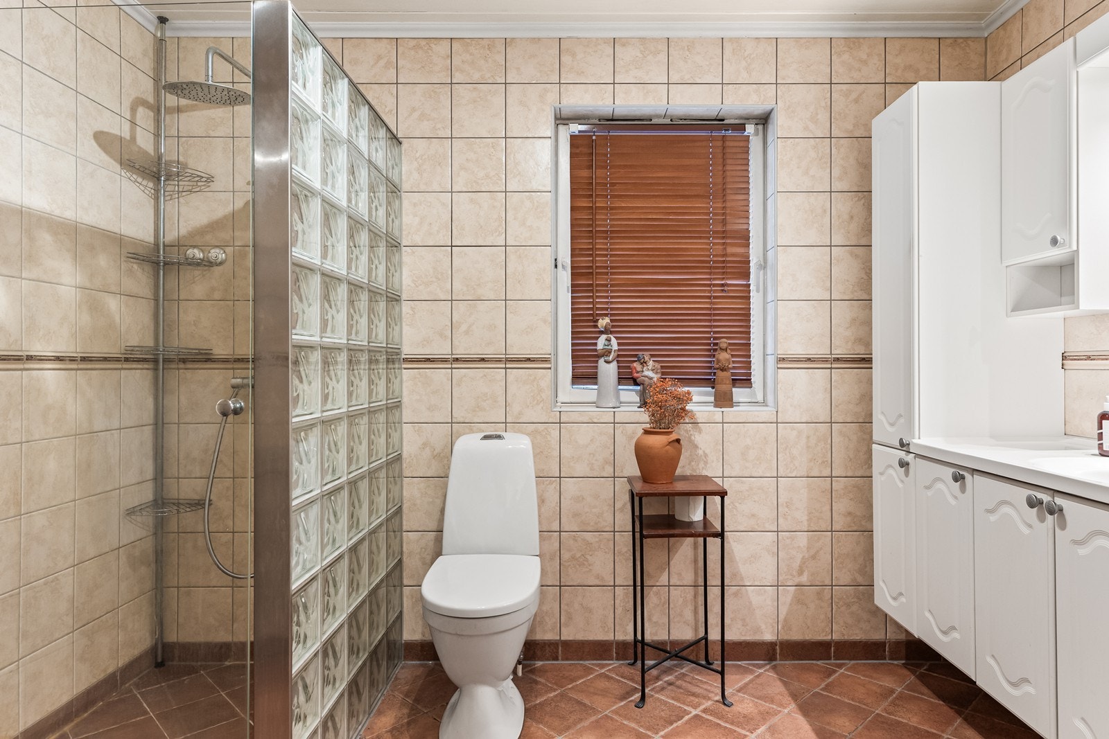 Boligens bad er helfliset og har en romslig dusjnisje med glassbyggerstein. Galleribilde