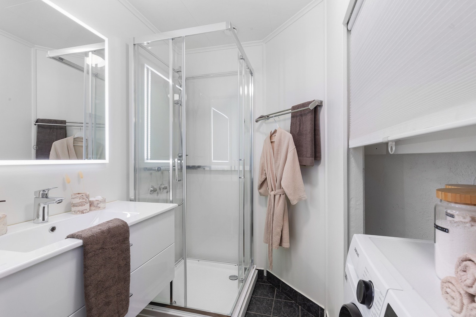 Lyst bad med praktiske skuffer, speil med god belysning og egen nisje til vaskemaskin Galleribilde