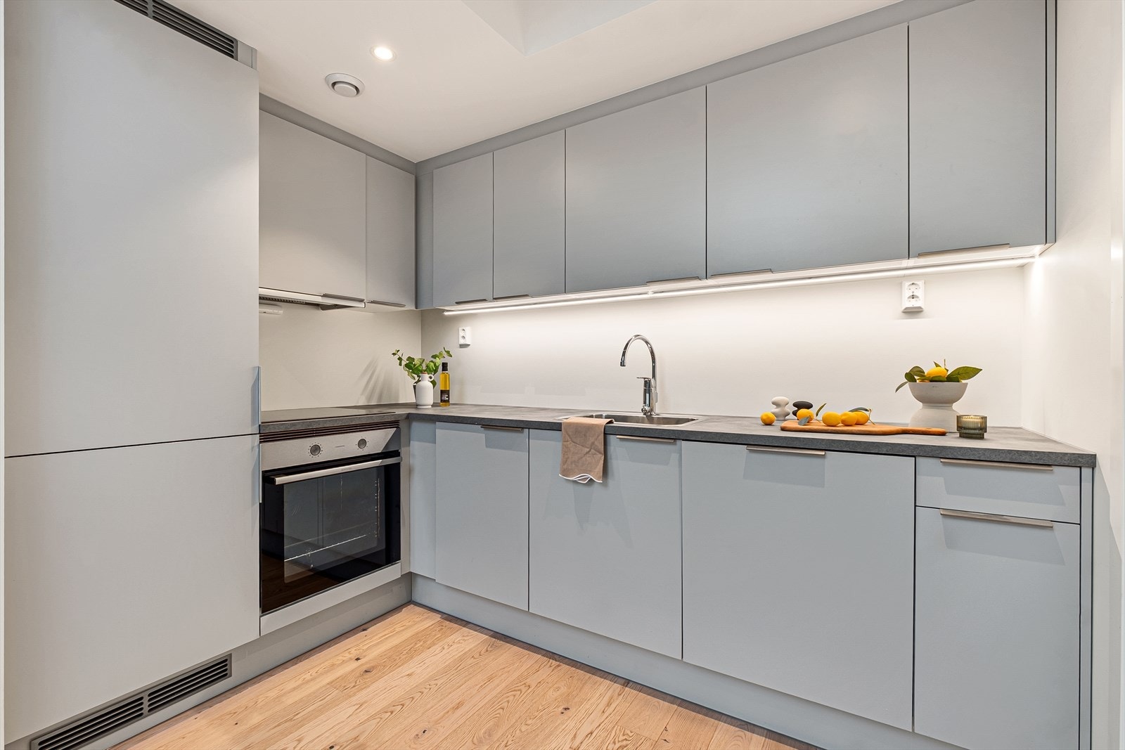 Kjøkkenet har slette fronter, benkeplate i laminat med nedfelt servant og waterguard, og integrerte hvitevarer. Galleribilde