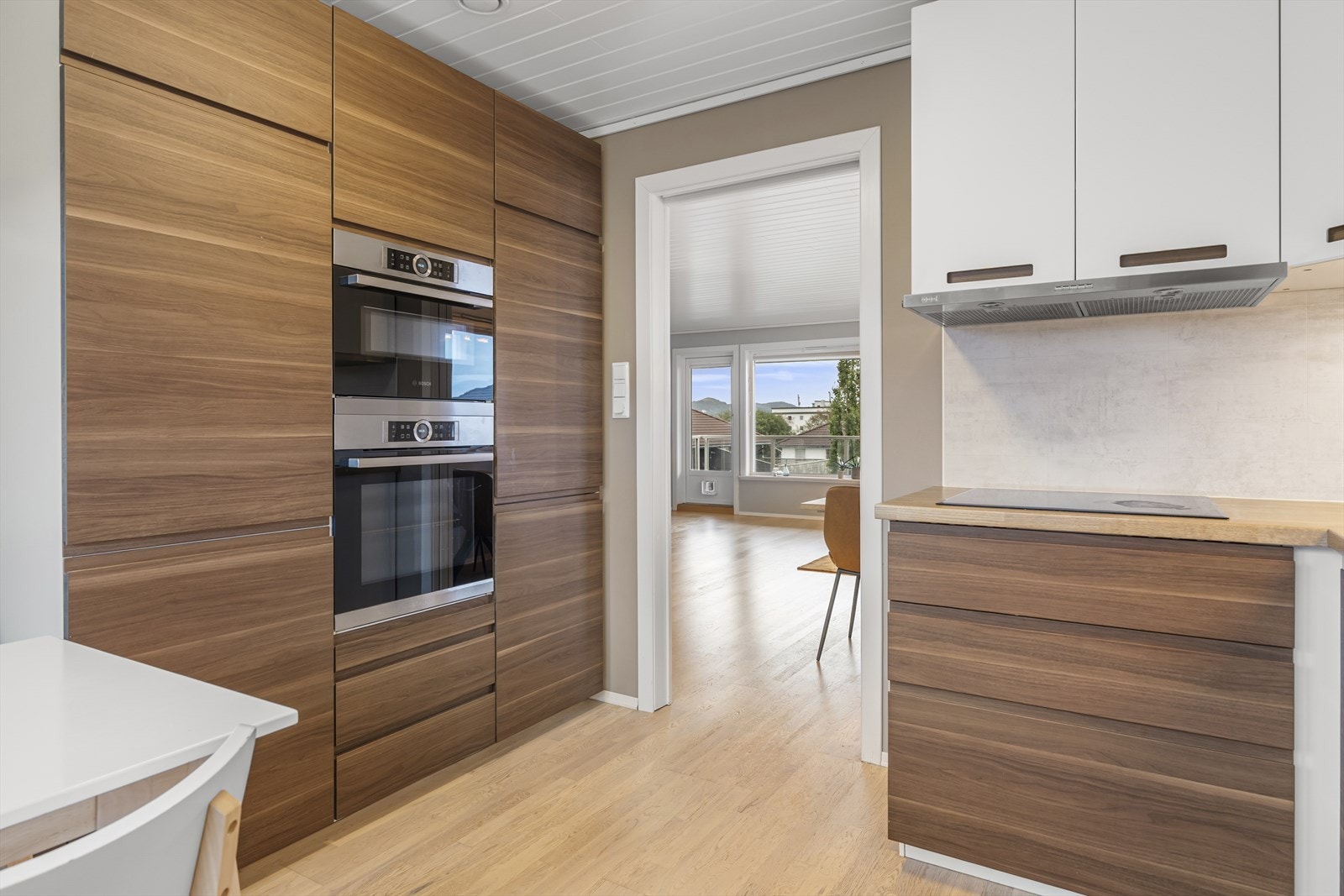 Fra stuen er det skyvedør inn til et nyere kjøkken, der samme type parkett bidrar til en flytende overgang mellom rommene. Galleribilde