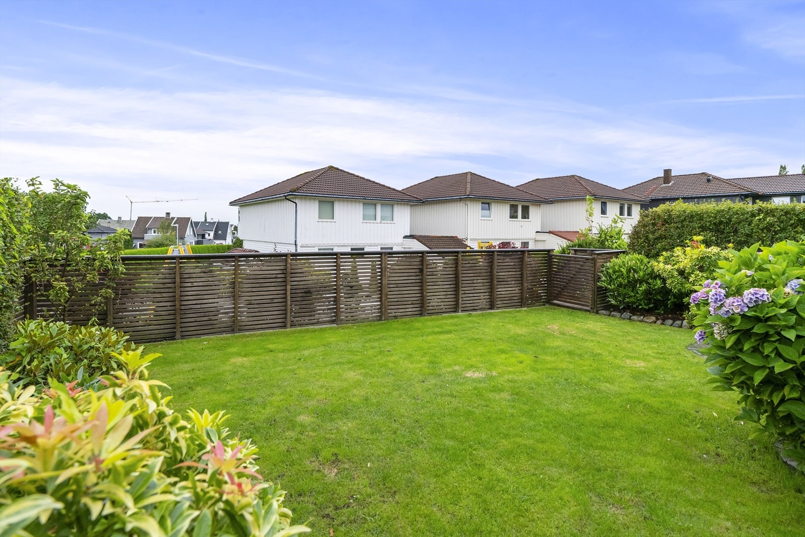 Hagen er lettholdt og velstelt, pent opparbeidet med busker, skifersten, blomsterbed og flat gressplen. Utearealet rammes fint inn av hekker, et gjerde og en støttemur av stein. Galleribilde