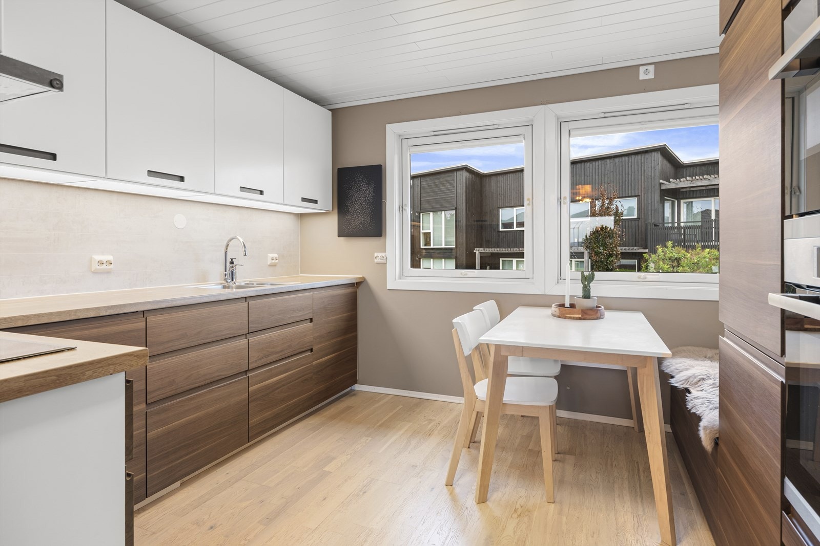 Kjøkkenet har god plass til kjøkkenbord og har en lekker innredning med glatte trefronter, hvite overskap og laminert benkeplate med dobbel oppvaskkum. Galleribilde