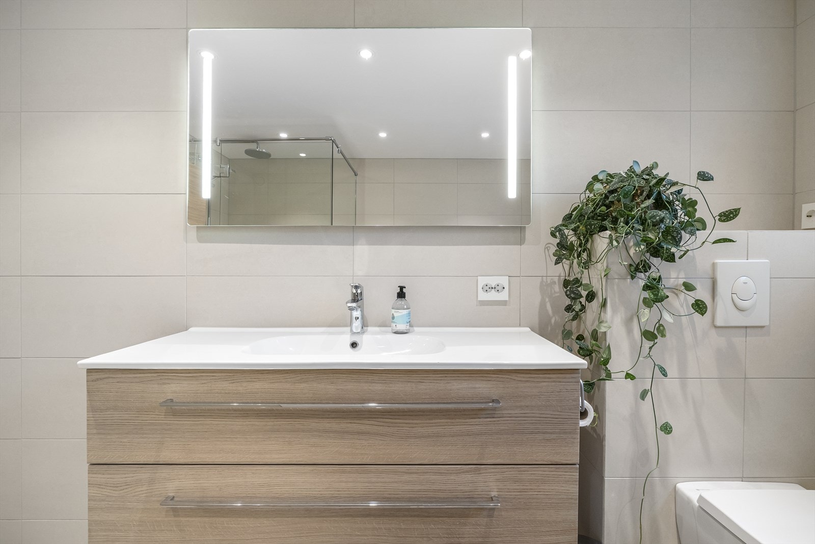 Baderomsinnredningen består av servant med trendy skuffer, matchende høyskap og et speil med integrert belysning. Galleribilde