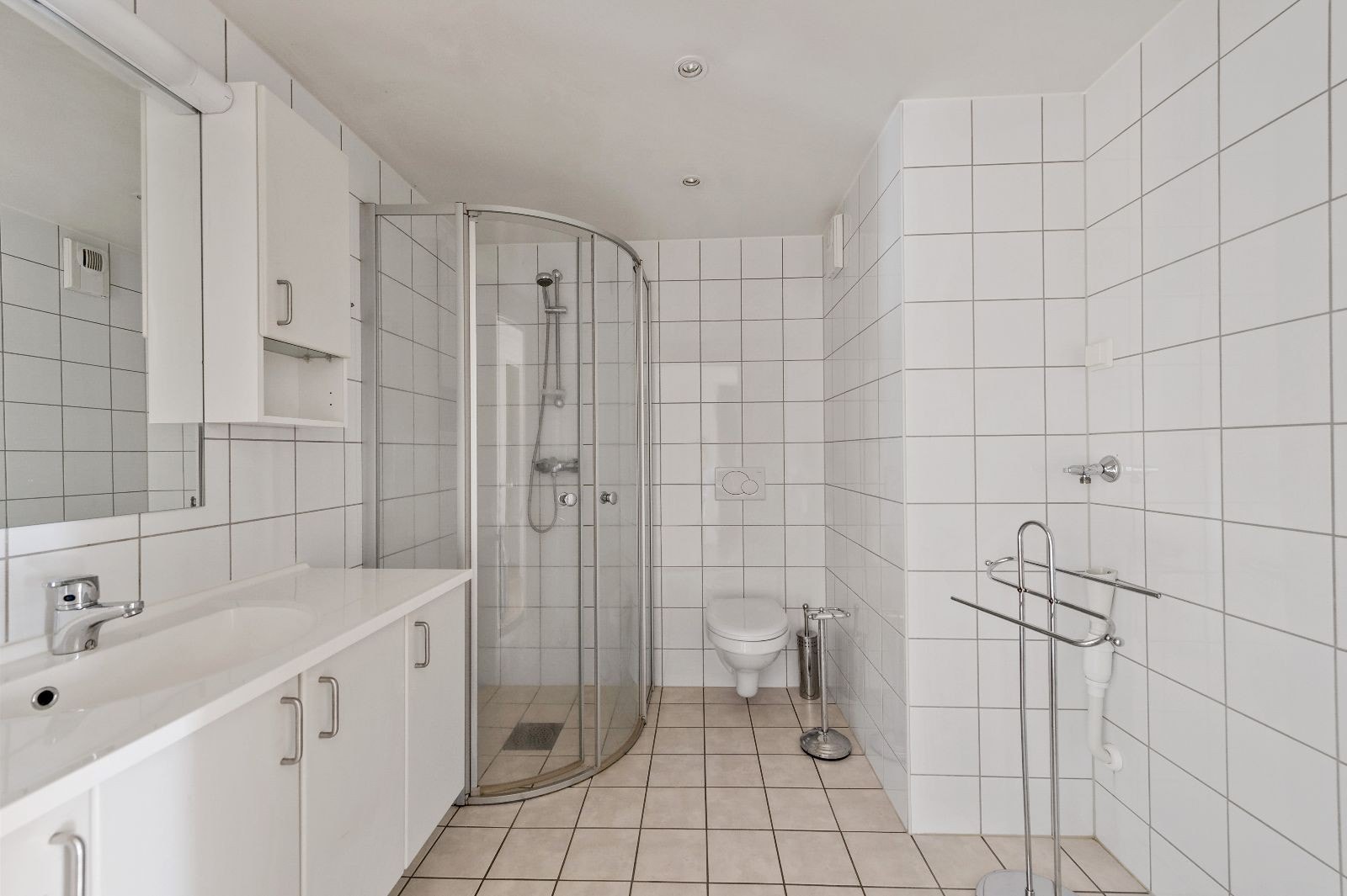 Flislagt bad med servant i innredning med mye plass til oppbevaring. Opplegg for vask og tørk Galleribilde