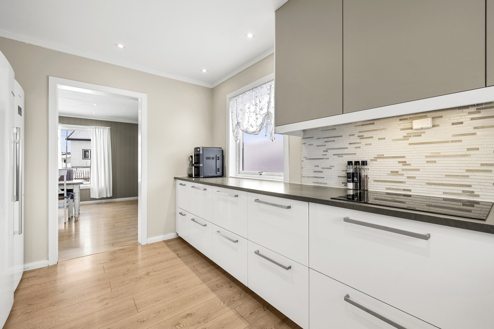 Kjøkkeninnredningen består av glatte fronter og laminat benkeplate med nedfelt kum i rustfritt stål. Stekeovn, platetopp og kaffemaskin er integrert i innredningen. Galleribilde