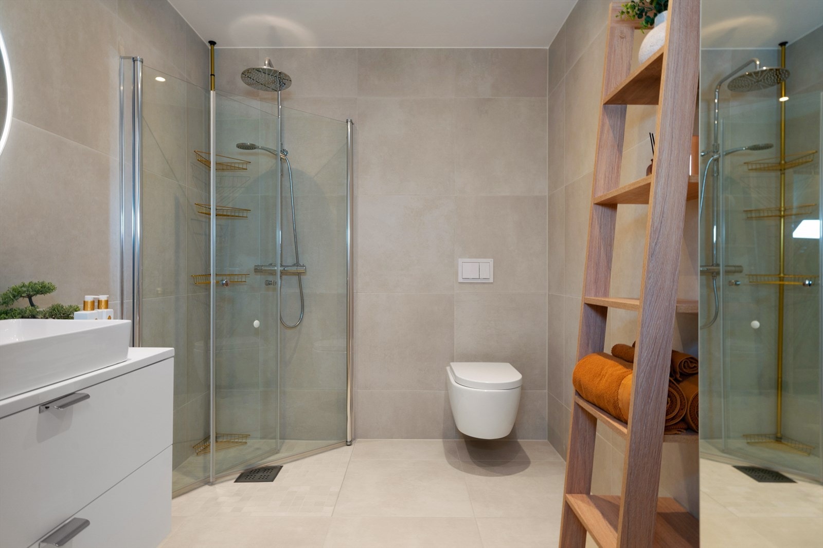 Delikat flislagt bad innredet med dusjhjørne, servant med innredning, speil med belysning og vegghengt toalett. Galleribilde