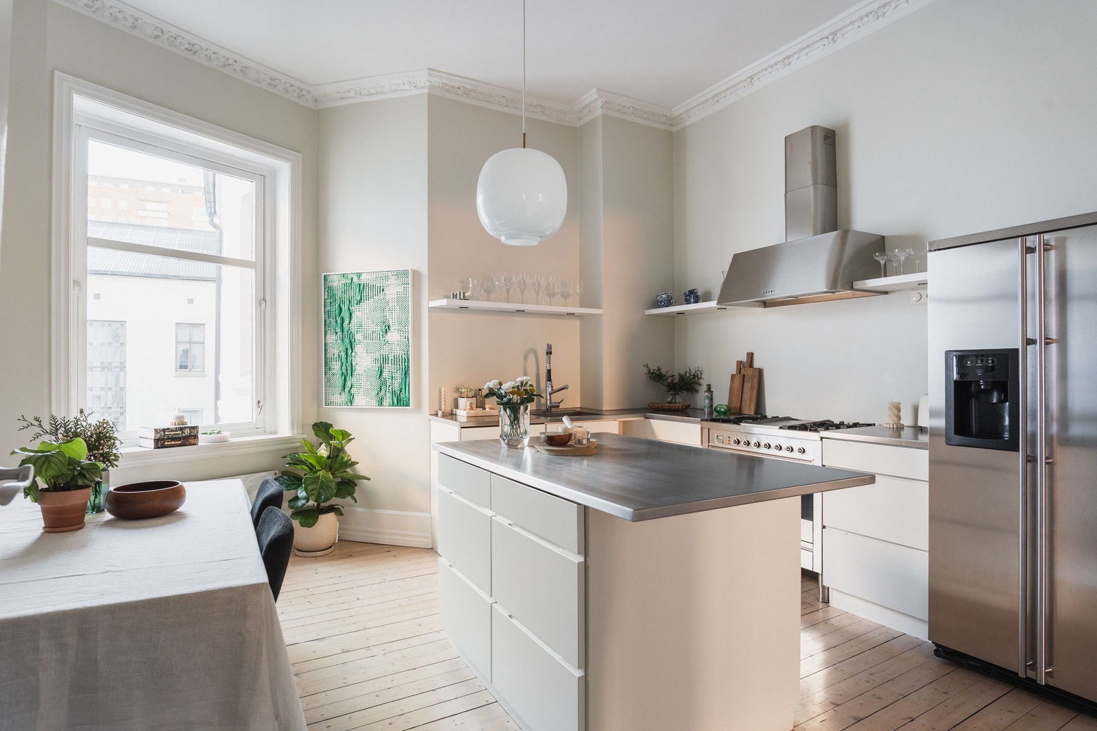 Kjøkkenet har et delikat og minimalistisk uttrykk med glatte, hvite fronter kombinert med benkeplate i stål. Galleribilde