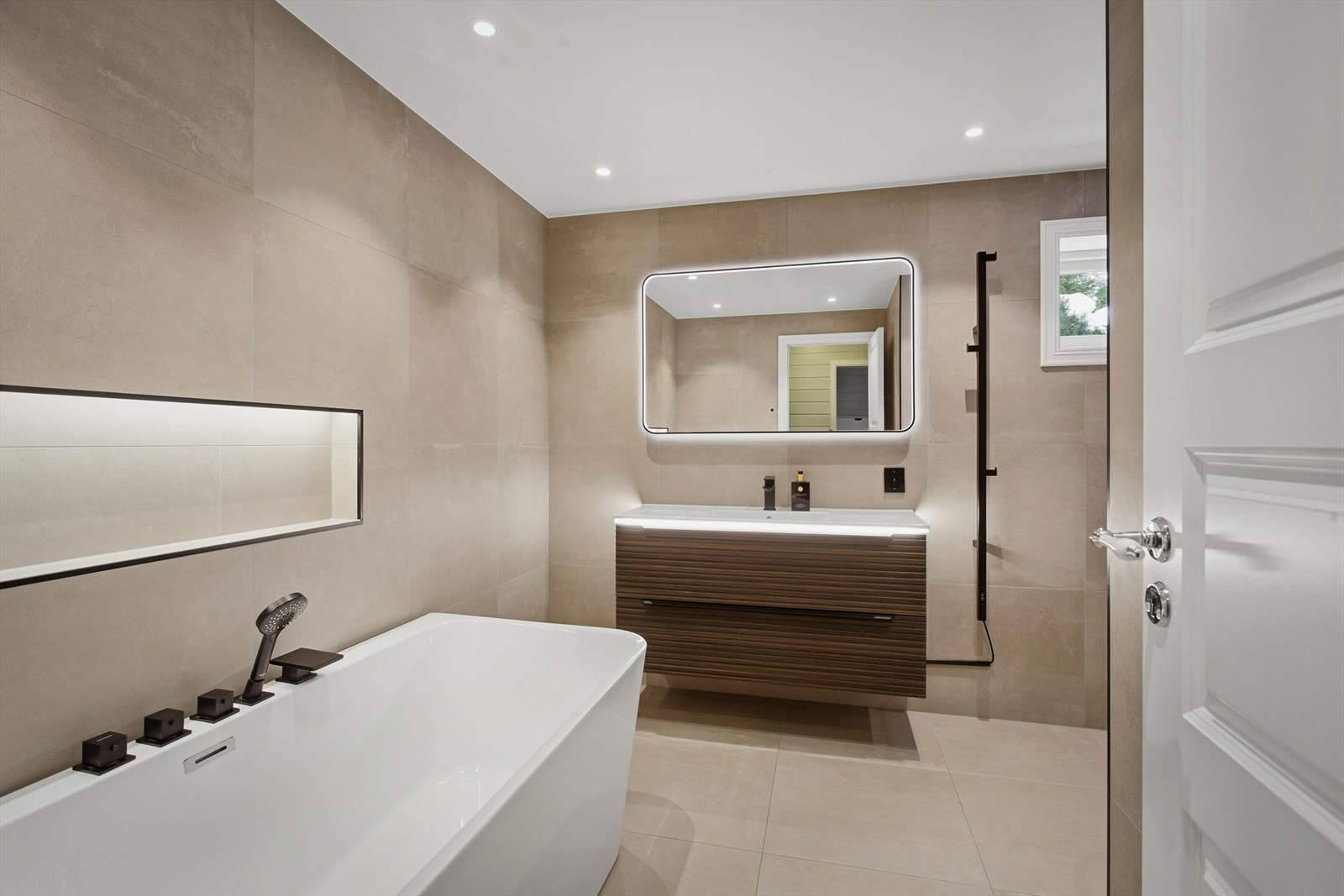 Den helhetlige fargepaletten i beige og naturtoner skaper en rolig og elegant atmosfære, mens de store flisene gir både et tidløst uttrykk og en romslig følelse. Galleribilde