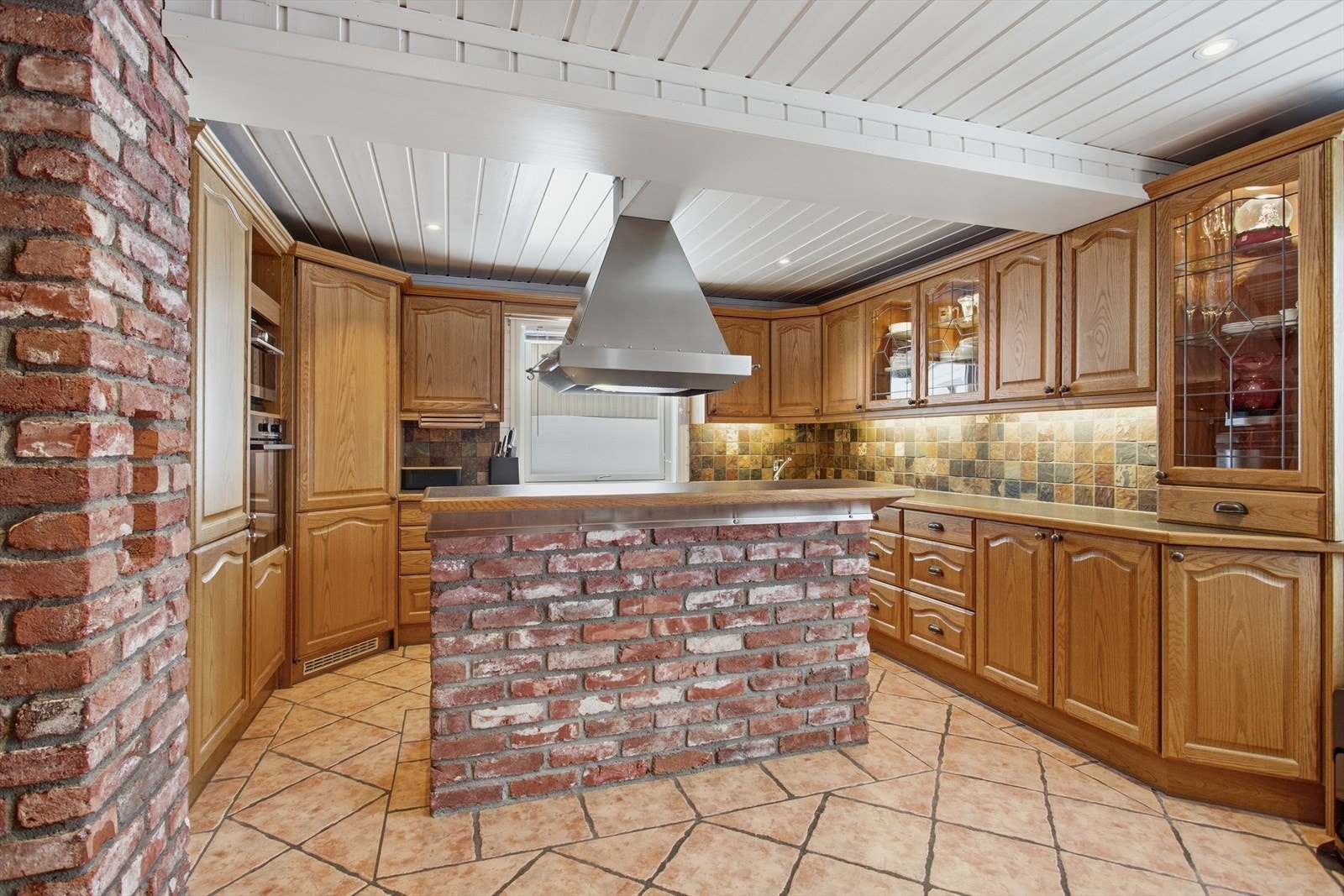 Muren harmonerer godt med både de varme gulvflisene og kjøkkenets treverk, og skaper et helhetlig uttrykk som blir både lunt og tidløst. Galleribilde