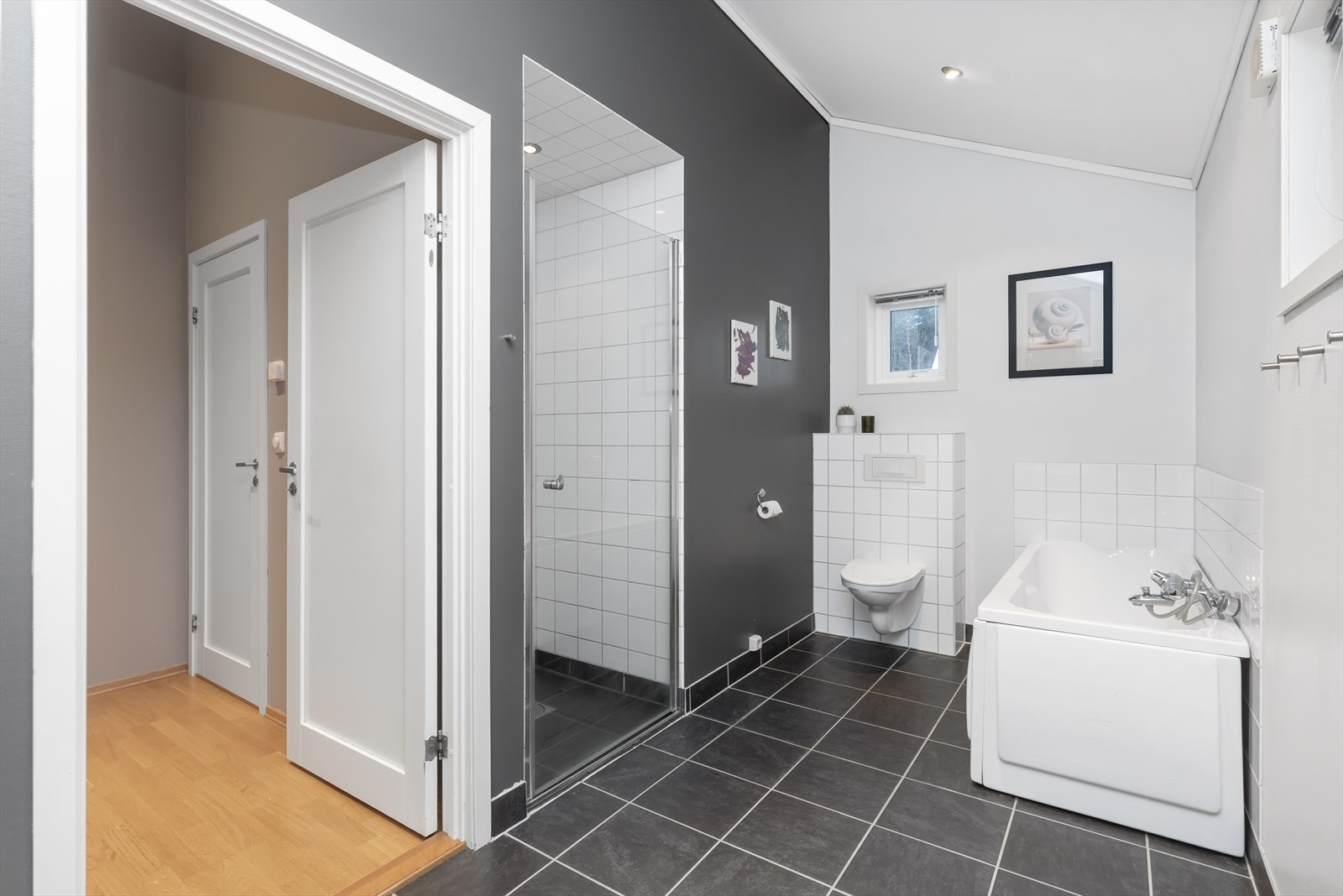 Badet er utstyrt med nedfelt servant, veggmontert toalett, badekar og dusjnisje. Galleribilde