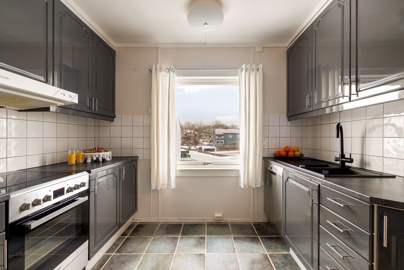 Kjøkkenet har flis på gulv, malte vegger og malt tak. Flis mellom over- og underskap. Galleribilde