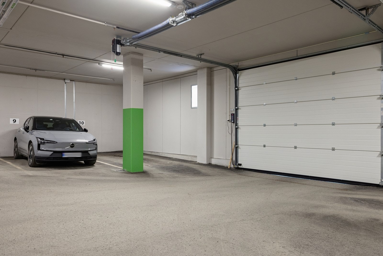 Parkeringsplass med elbil lader i lukket garasjeanlegg. Galleribilde