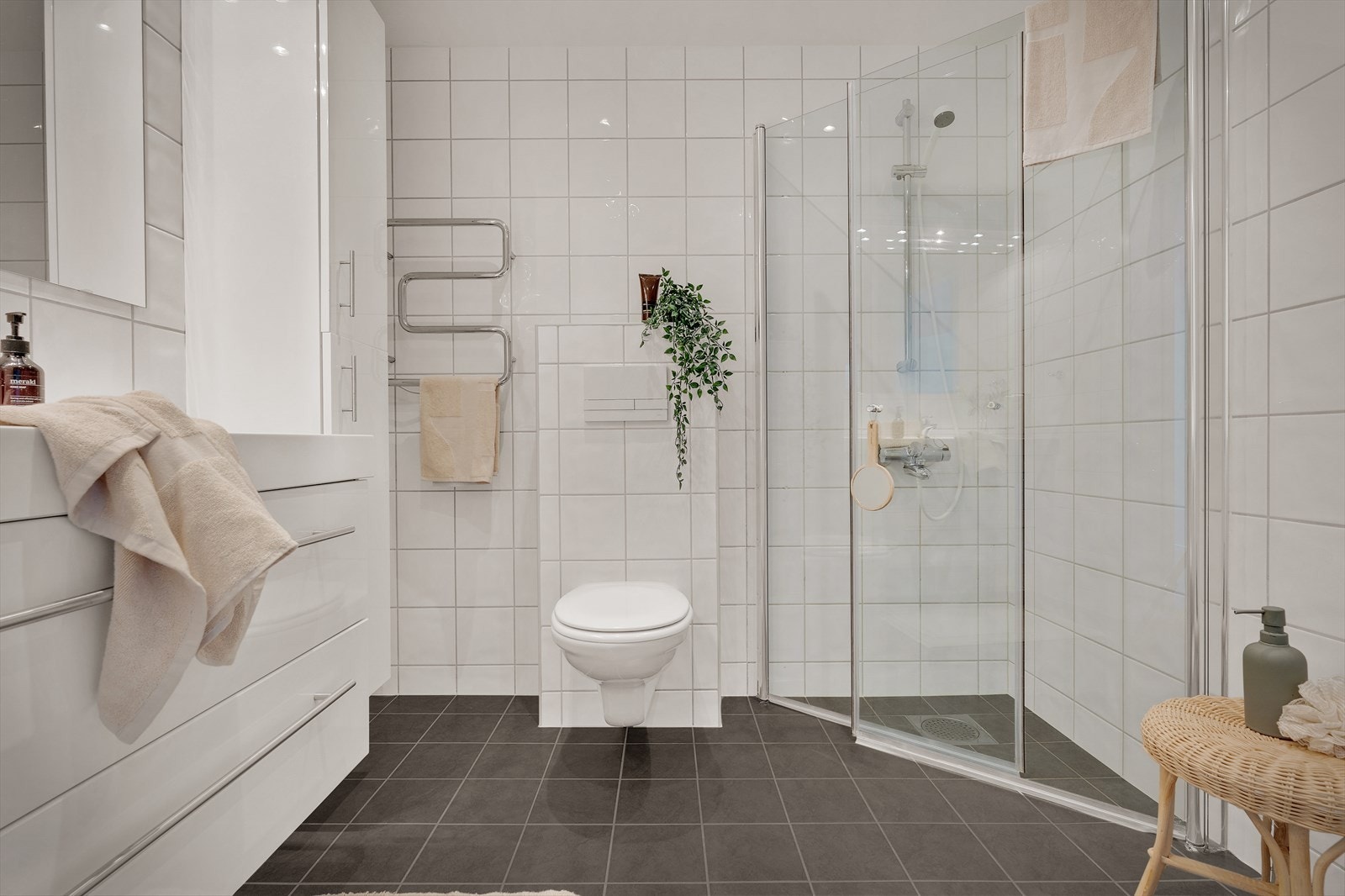 Badet er utstyrt med foldedører i dusj, veggtoalett og baderomsinnredning med heldekkende servant, samt belyst speil Galleribilde