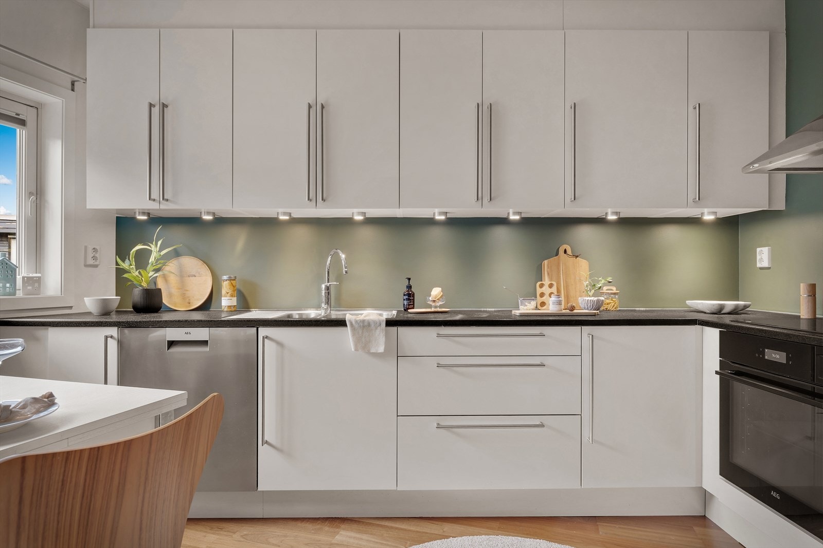 Kjøkkeninnredning med hvite glatte fronter og laminert benkeplate med planlimt kjøkkenvask Galleribilde