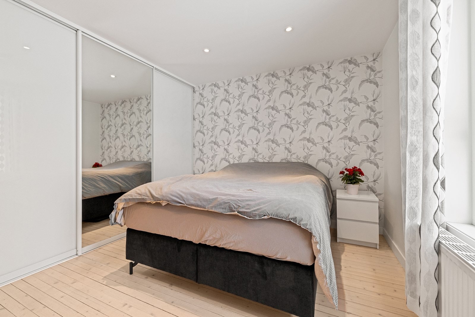 En stor skyvedørsgarderobe, hvorav én av dørene har speilfront, gir både plasseringsvennlighet og et luftig preg. Galleribilde