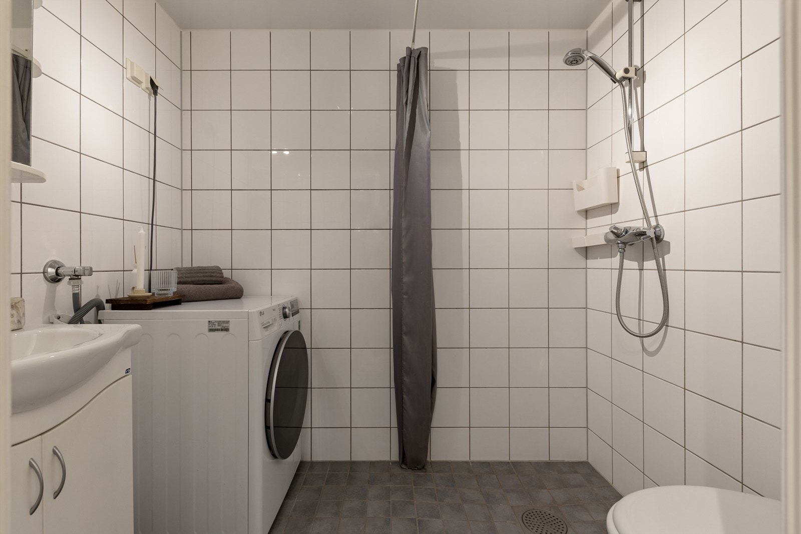 Badet er tidløst innredet med grå fliser på gulvet og hvite fliser på vegg. I gulvet har man også varmekabler for ekstra komfort. Galleribilde