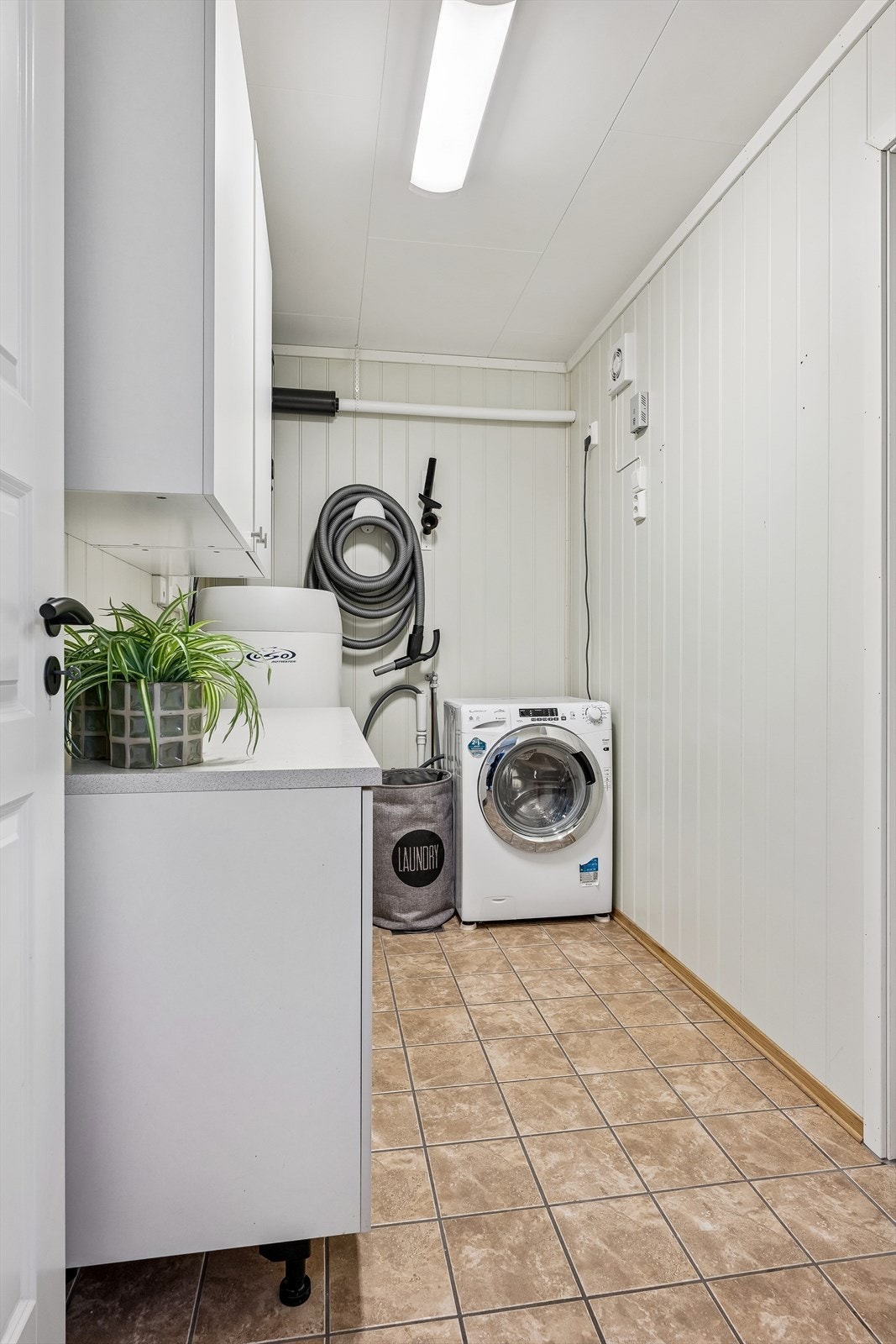 Praktisk, separat vaskerom med flislagt gulv. Her er også enheten for sentralstøvsugeren. Galleribilde