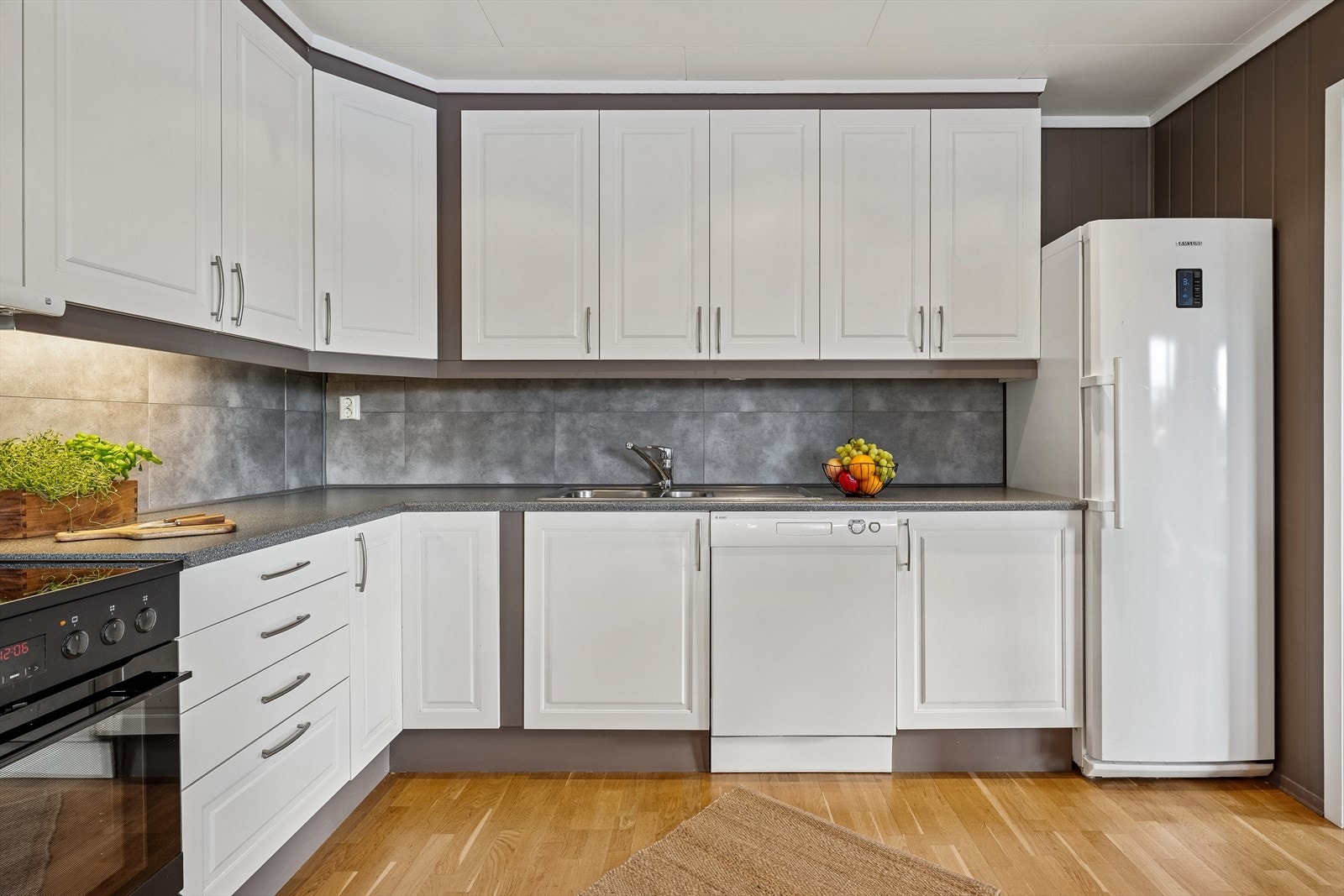 Innredningen har profilerte fronter, laminat benkeplate og er utstyrt med oppvaskmaskin og komfyr. Galleribilde